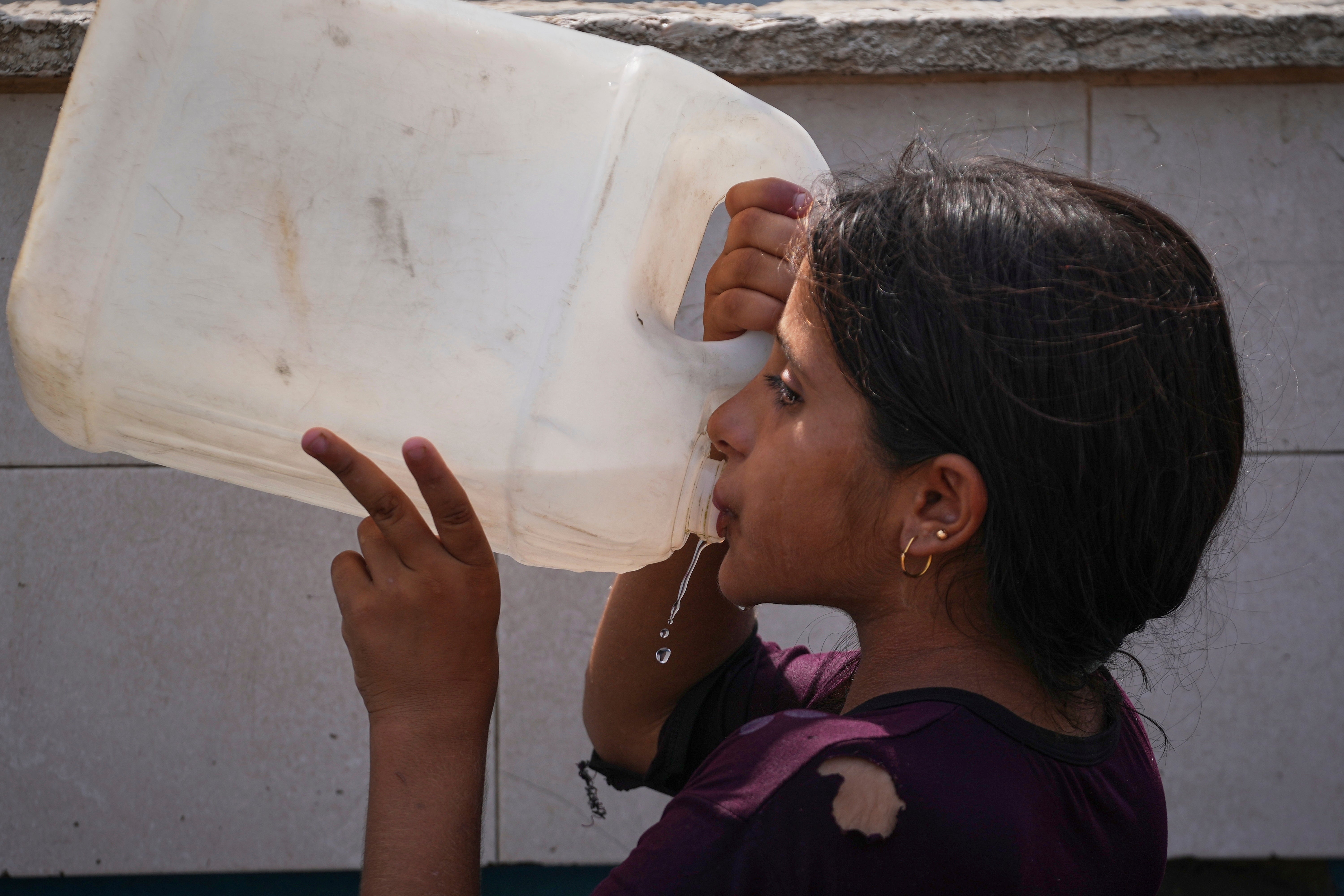 A Palestinian girl drinks water near a distribution centre in Deir al-Balah, in the central Gaza Strip