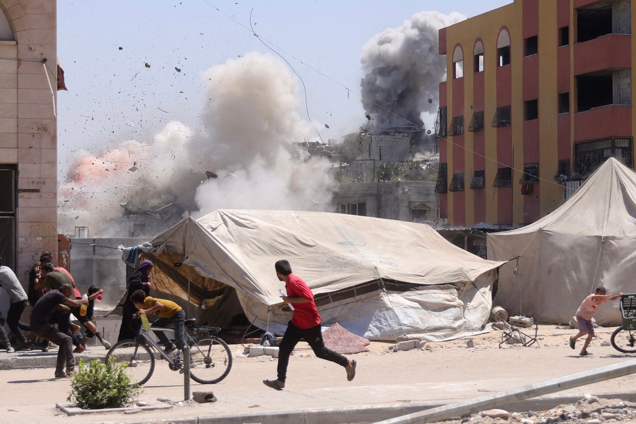 Palestinians rush for cover as smoke billows after an Israeli strike on a building in Jabalia, north of Gaza City, on Wednesday