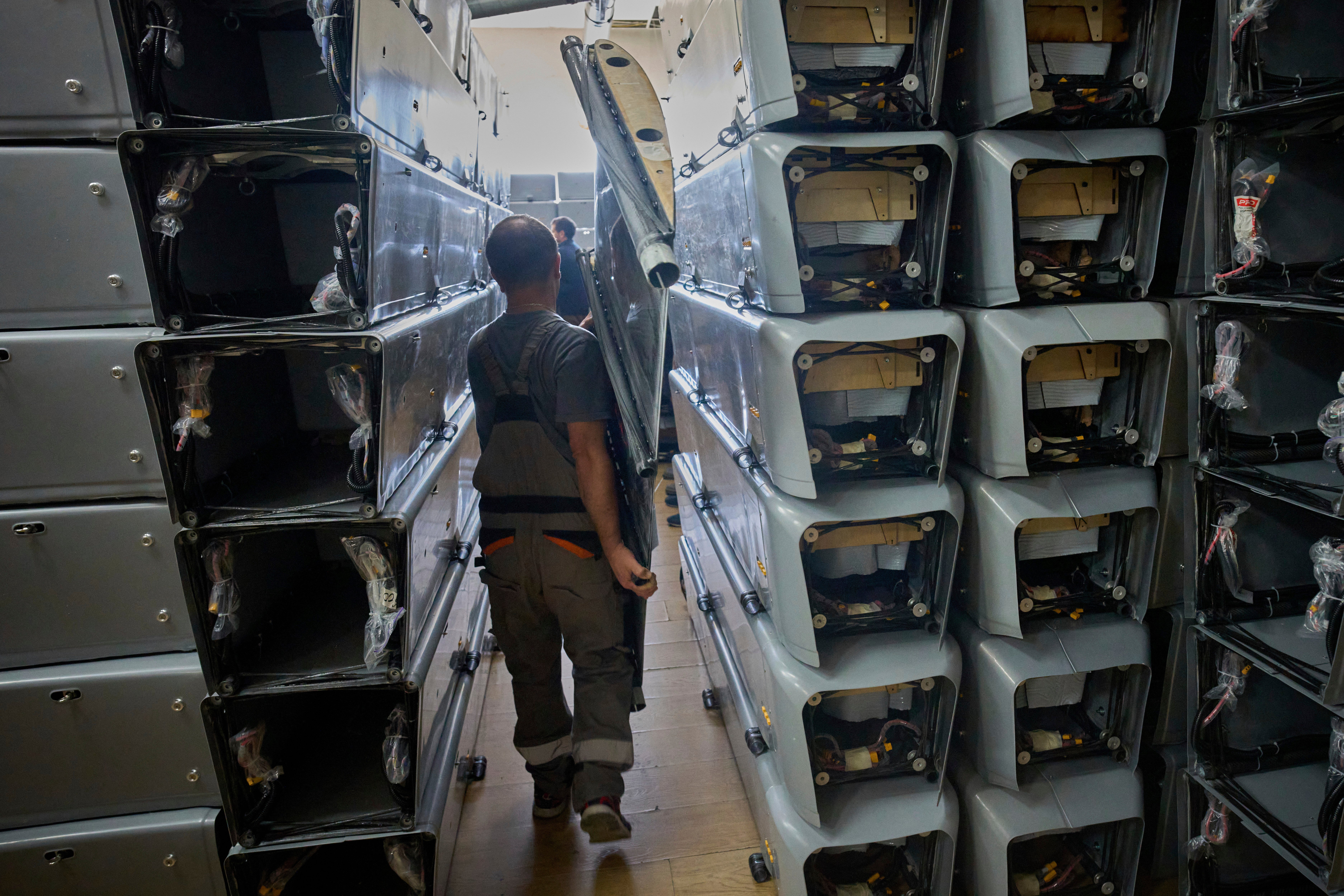 A worker carries part of a combat drone at Fire Point's secret factory in Ukraine