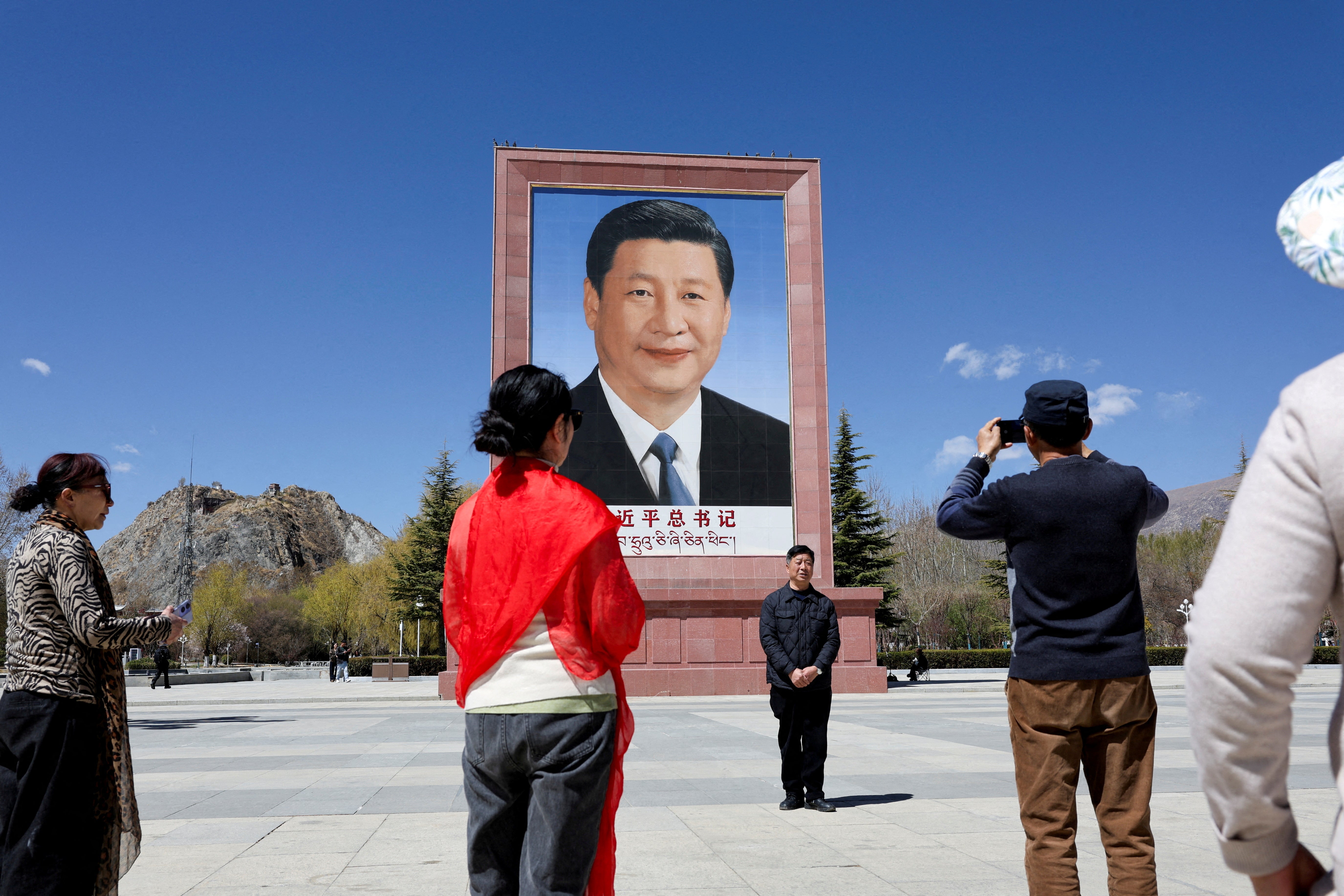 File. People take photo in front of a large portrait of Chinese President Xi Jinping, during a government-organised tour, at Potala Palace Square in Lhasa, Tibet Autonomous Region