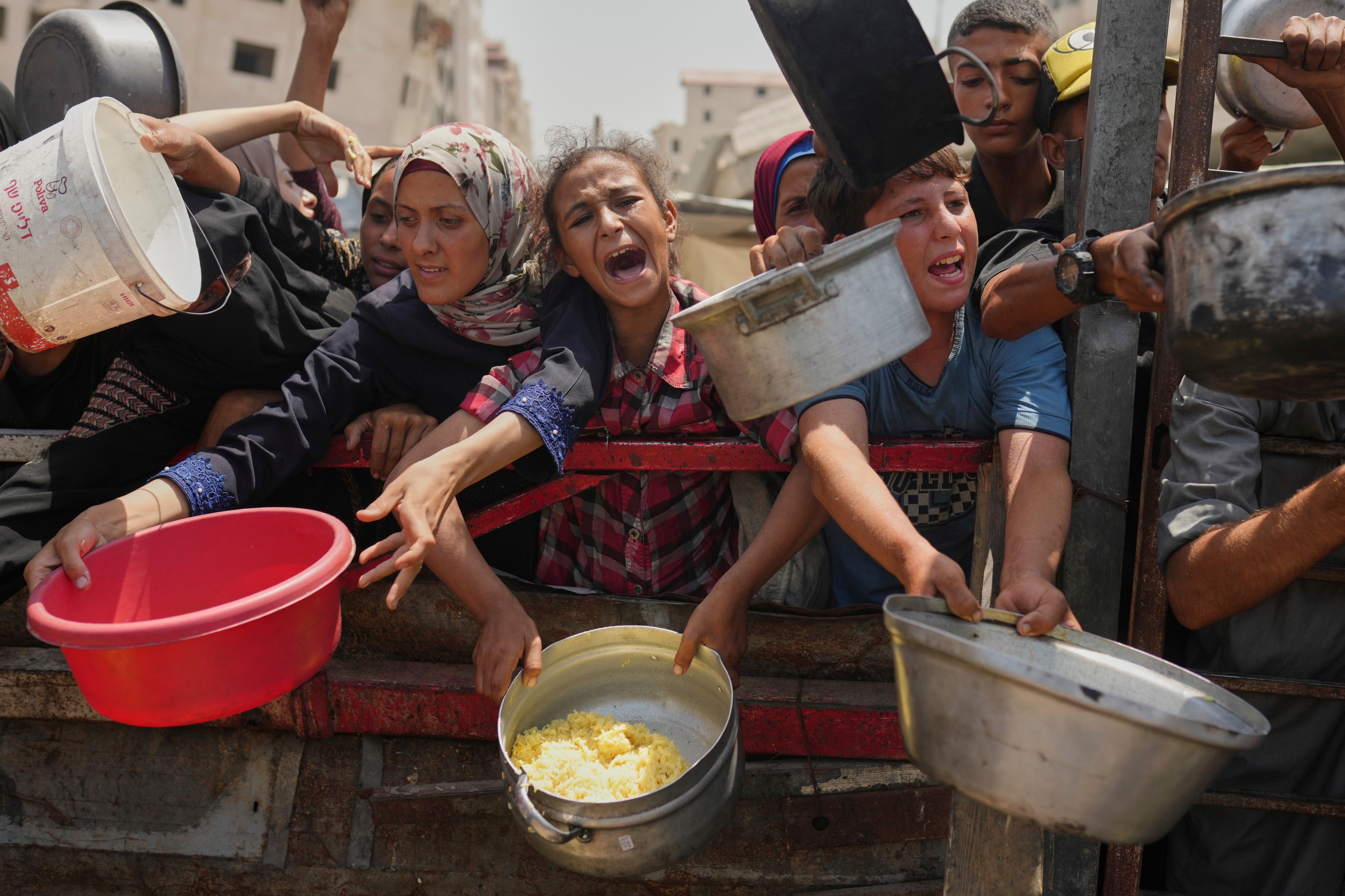 Palestinians struggle to get donated food at a community kitchen in Gaza City, northern Gaza Strip, Saturday, Aug. 16, 2025