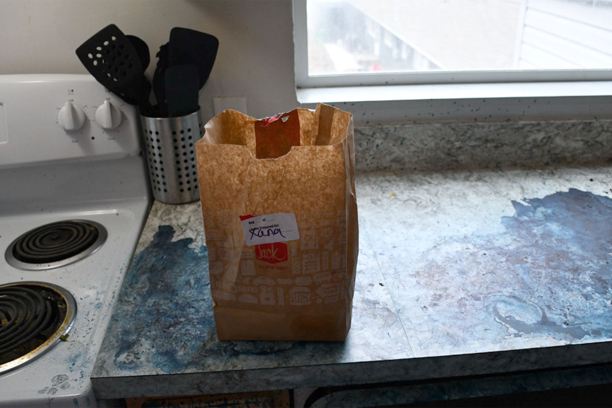 Xana’s half-eaten DoorDash order sits in a crumpled paper bag on the counter in the kitchen