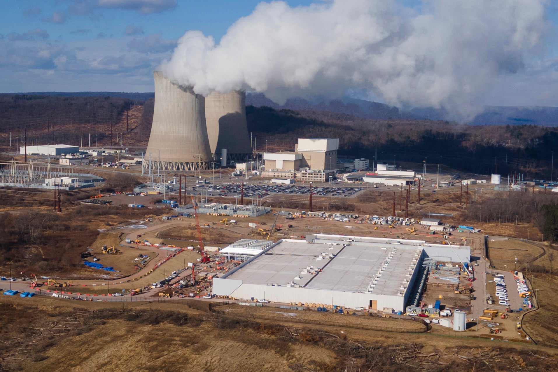 A data farm owned by Amazon Web Services, front right, is under construction next to the Susquehanna nuclear power plant in Berwick, Pennsylvania. U.S. data farms used approximately 17 gigawatts of power in 2022. A large nuclear power generator produces 1 gigawatt of energy, which can power between 300,000 and 750,000 U.S. homes