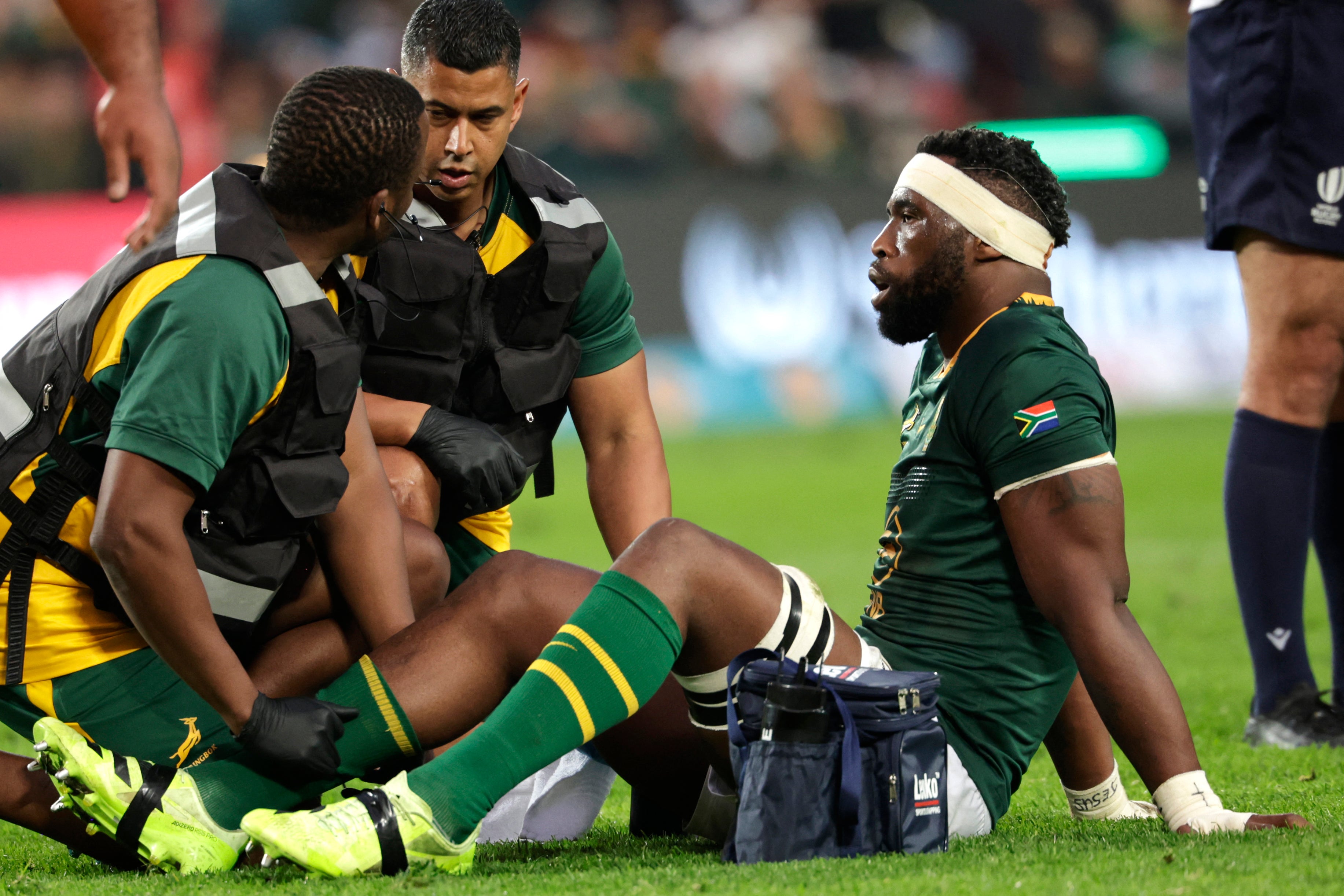 South Africa's number eight Siya Kolisi (R) recieves medical attention