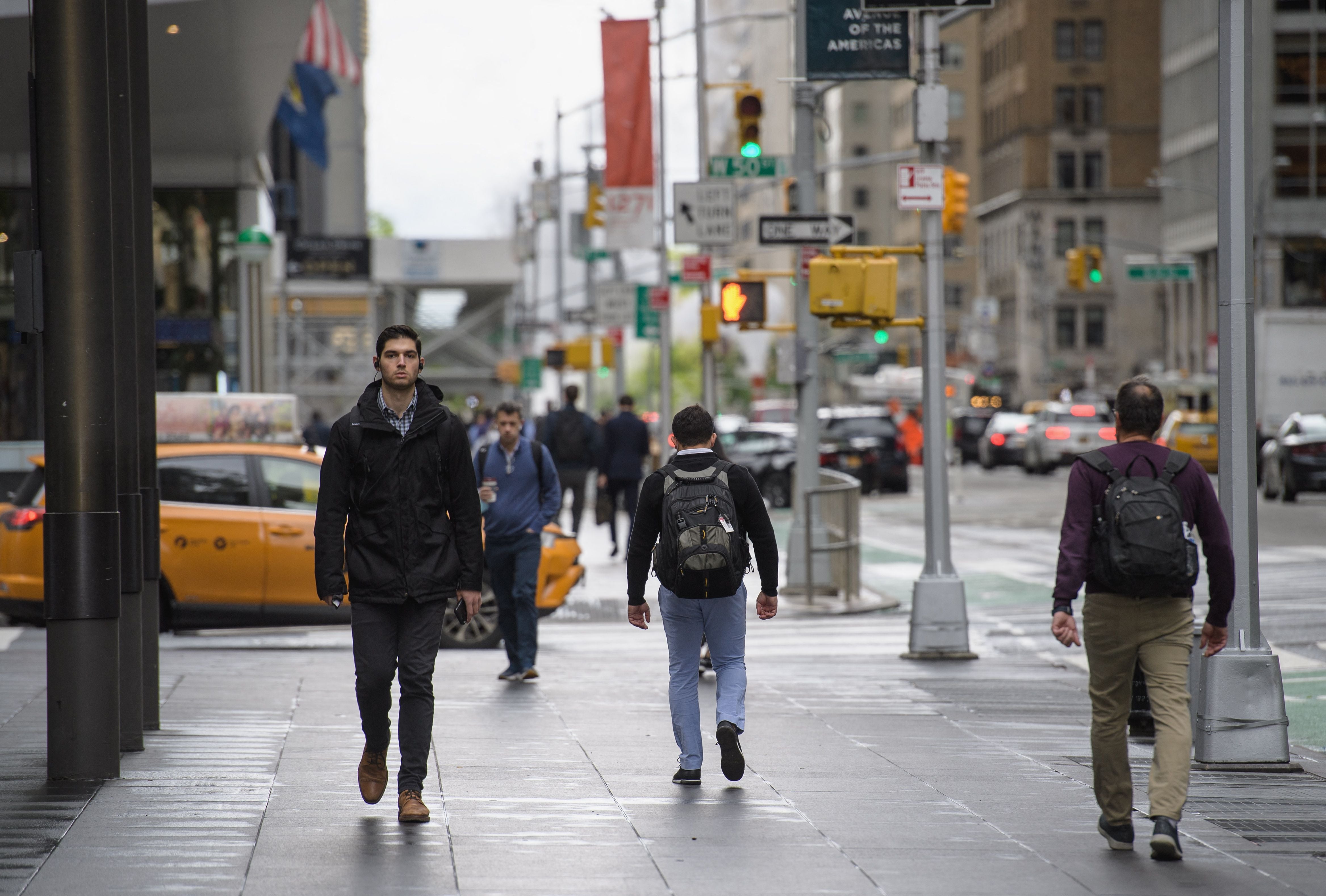 Workers walk across New York City streets. More American employees are ‘quiet quitting’ their jobs. Now, researchers say they know why