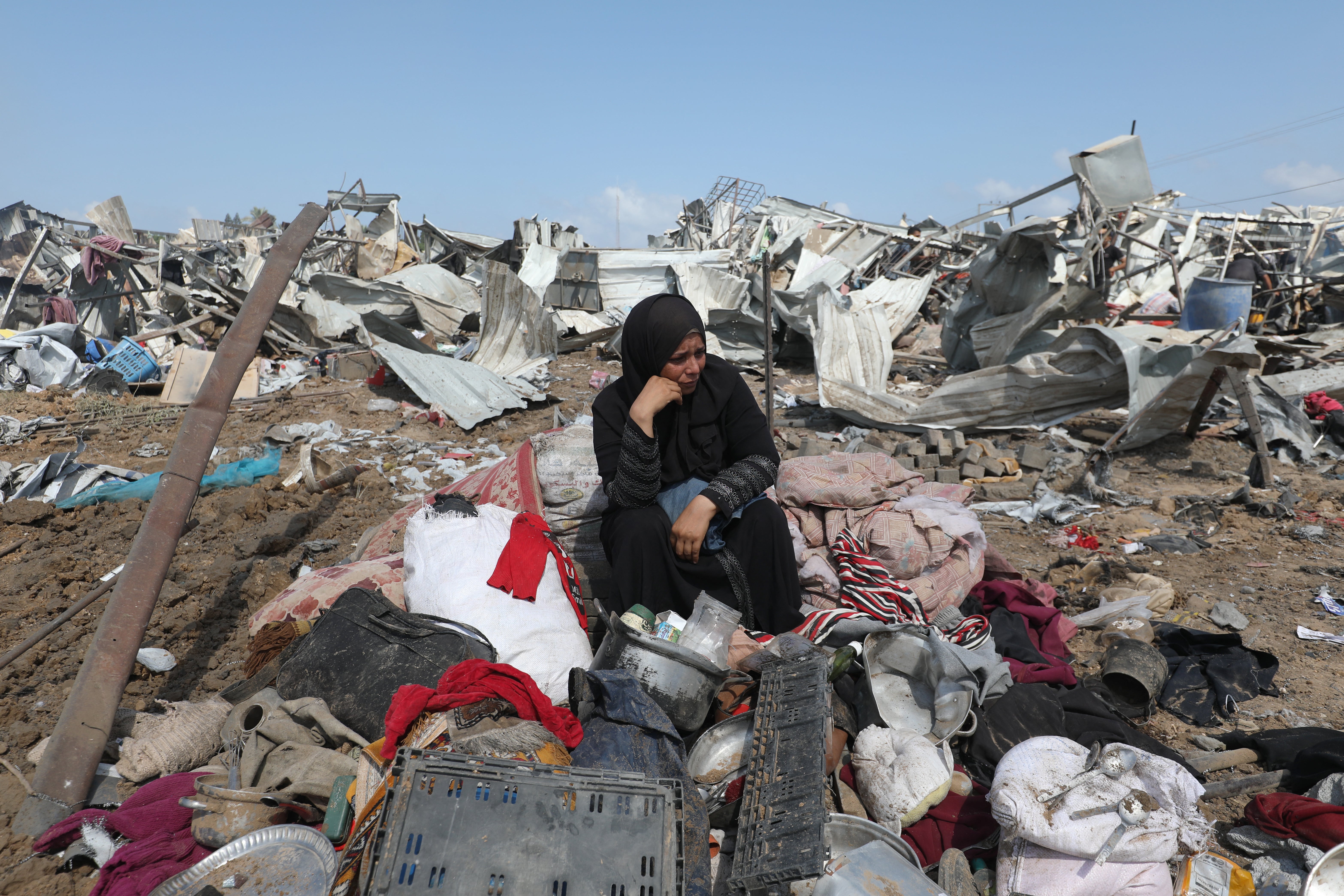 A Palestinian woman sits with her belongings after an Israeli strike on a camp for internally displaced people in Deir al-Balah, in the central Gaza Strip