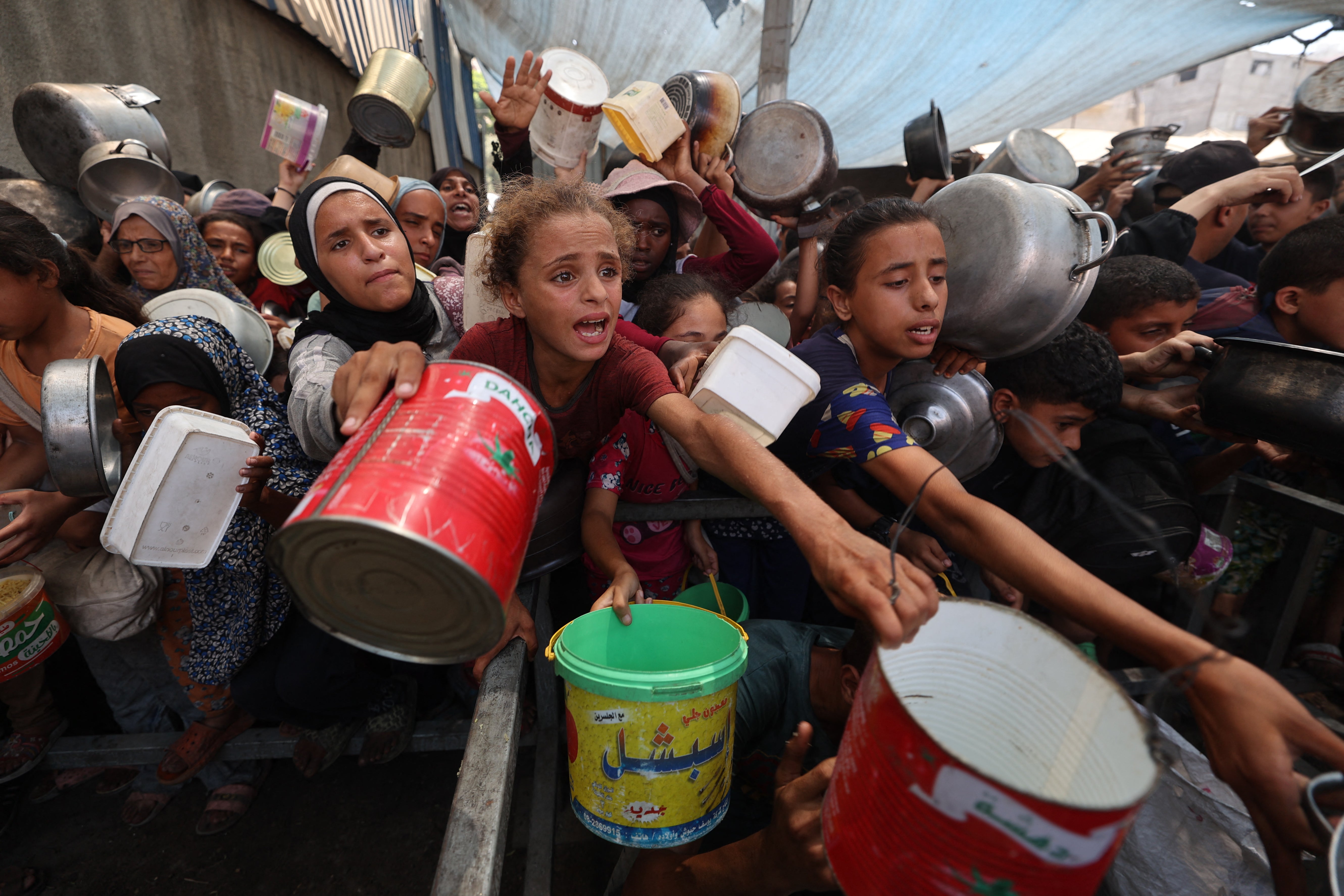 Palestinians gather to receive cooked meals from a food distribution center in the Nuseirat refugee camp