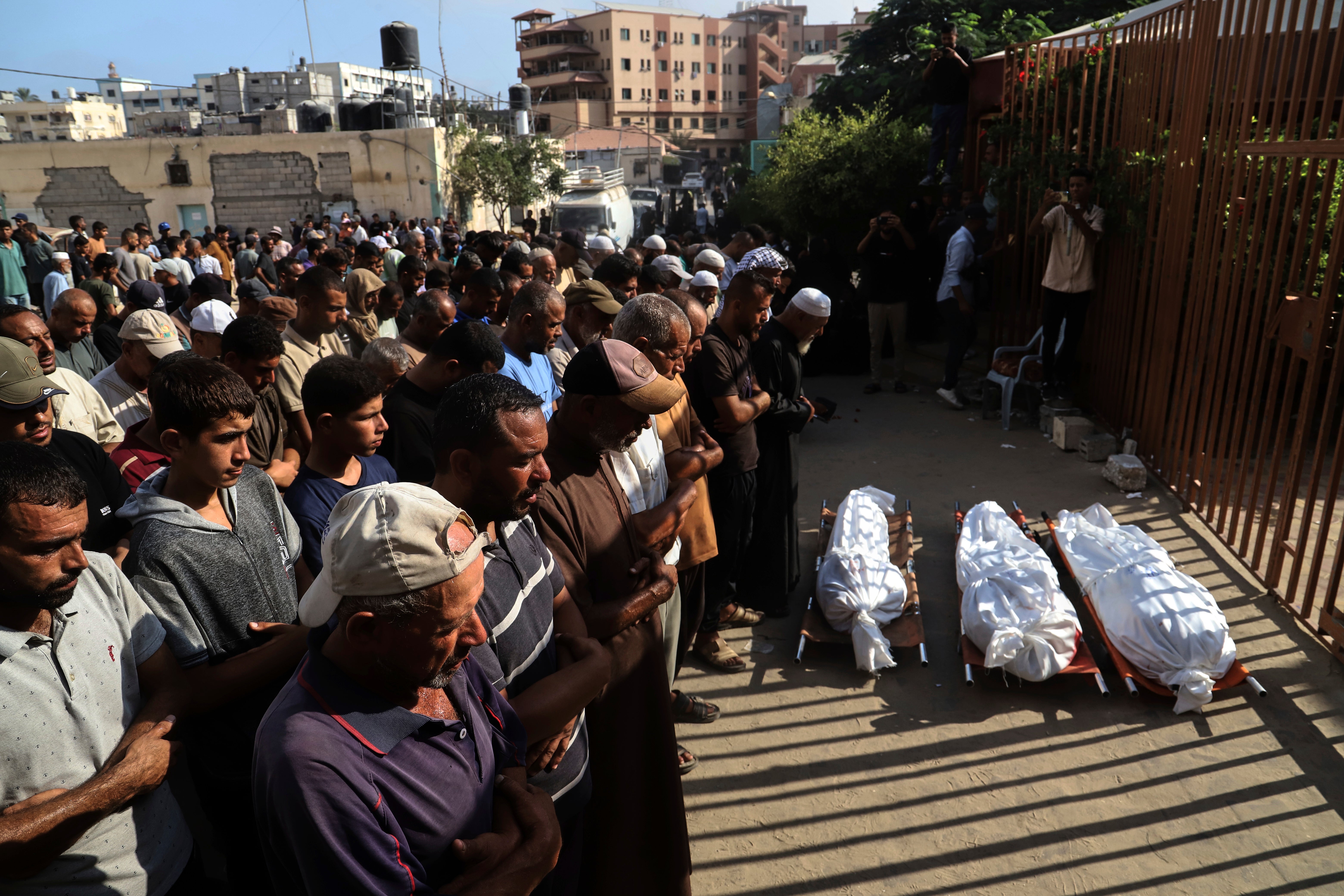 Mourners pray over the bodies of three Palestinians killed in Israeli strikes