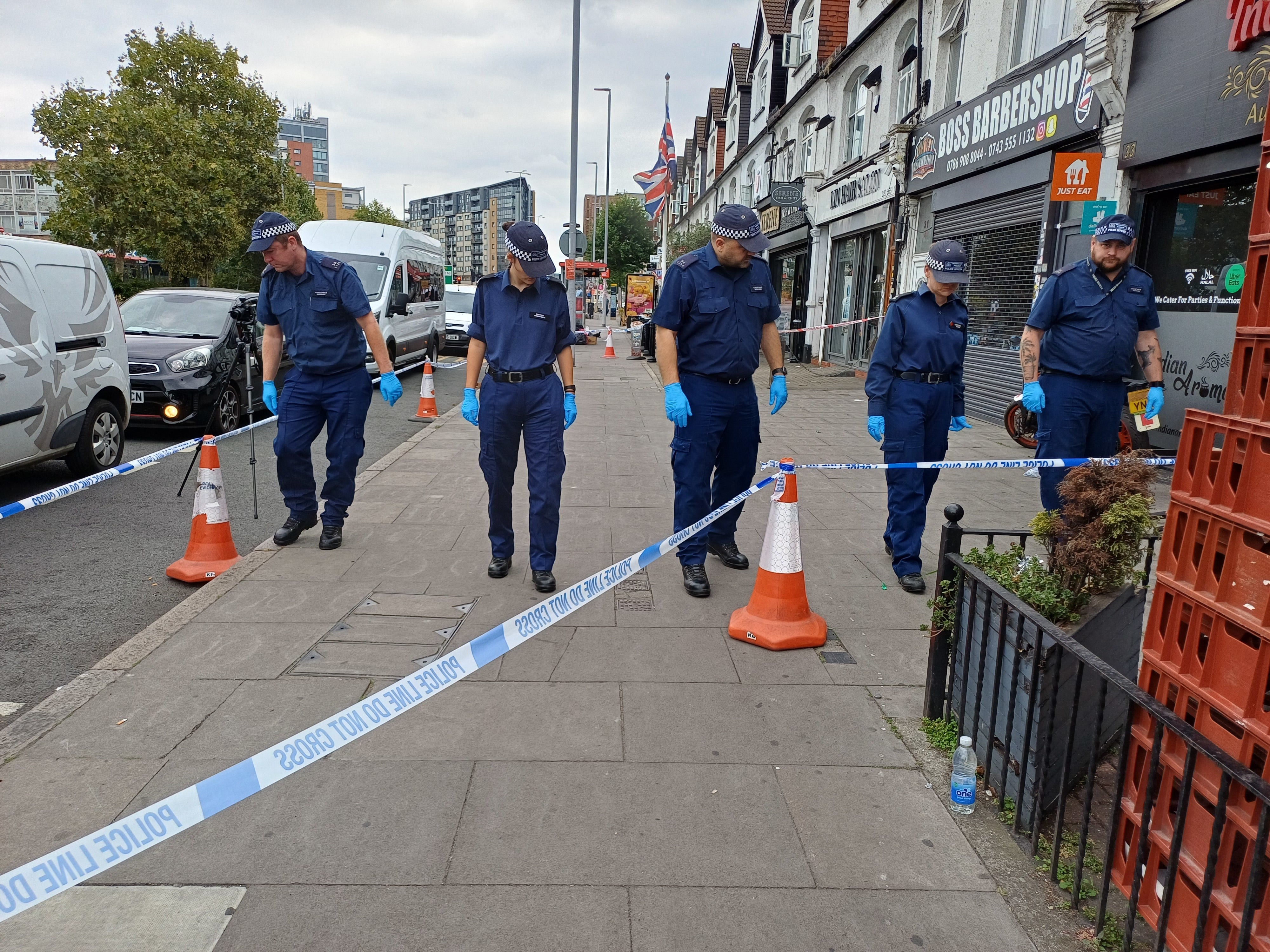 Police officers search the area on Woodford Avenue in Ilford (Helen William/PA)