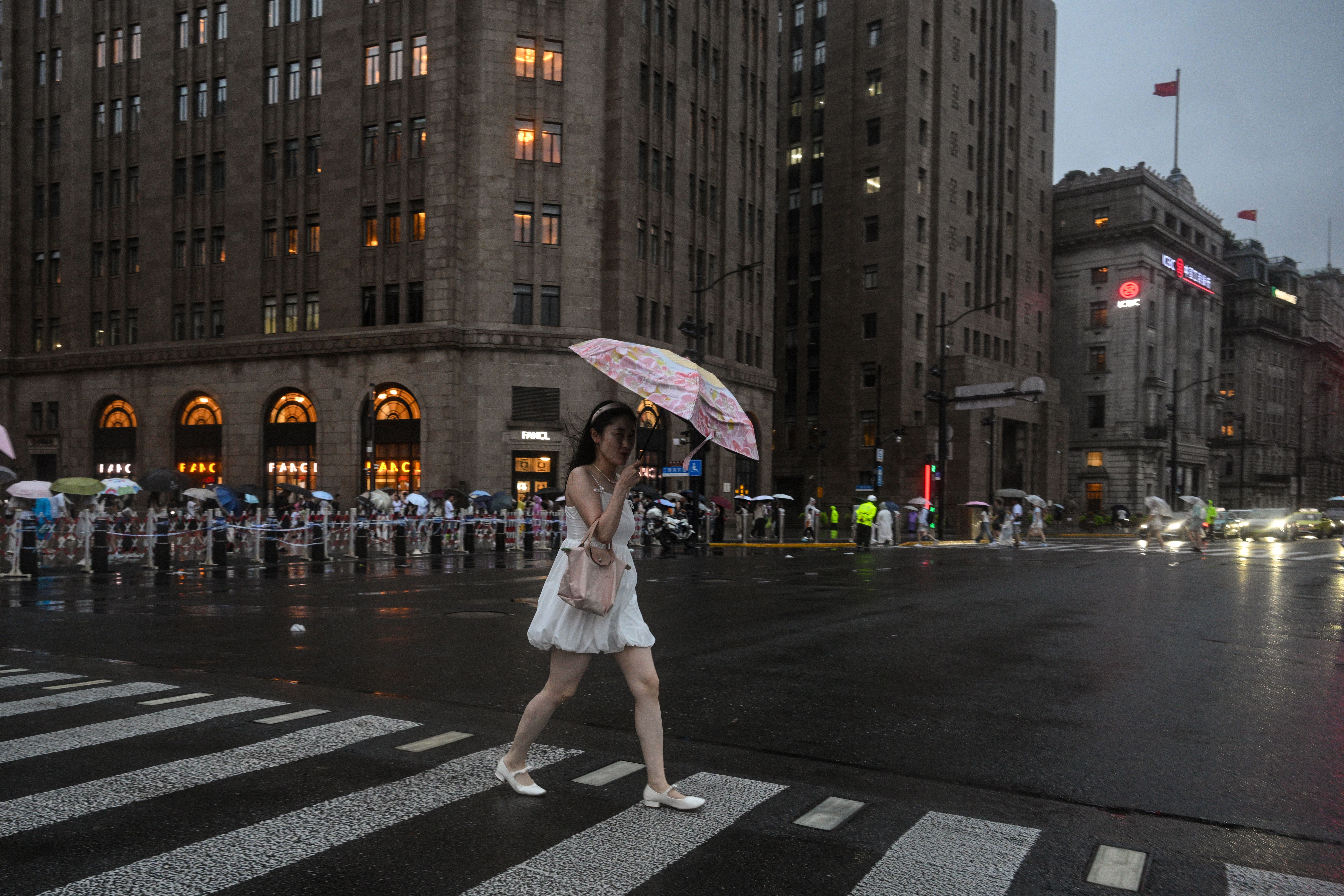 A woman uses an umbrella during the passage of Typhoon Co-May on The Bund, in Shanghai on 30 July 2025