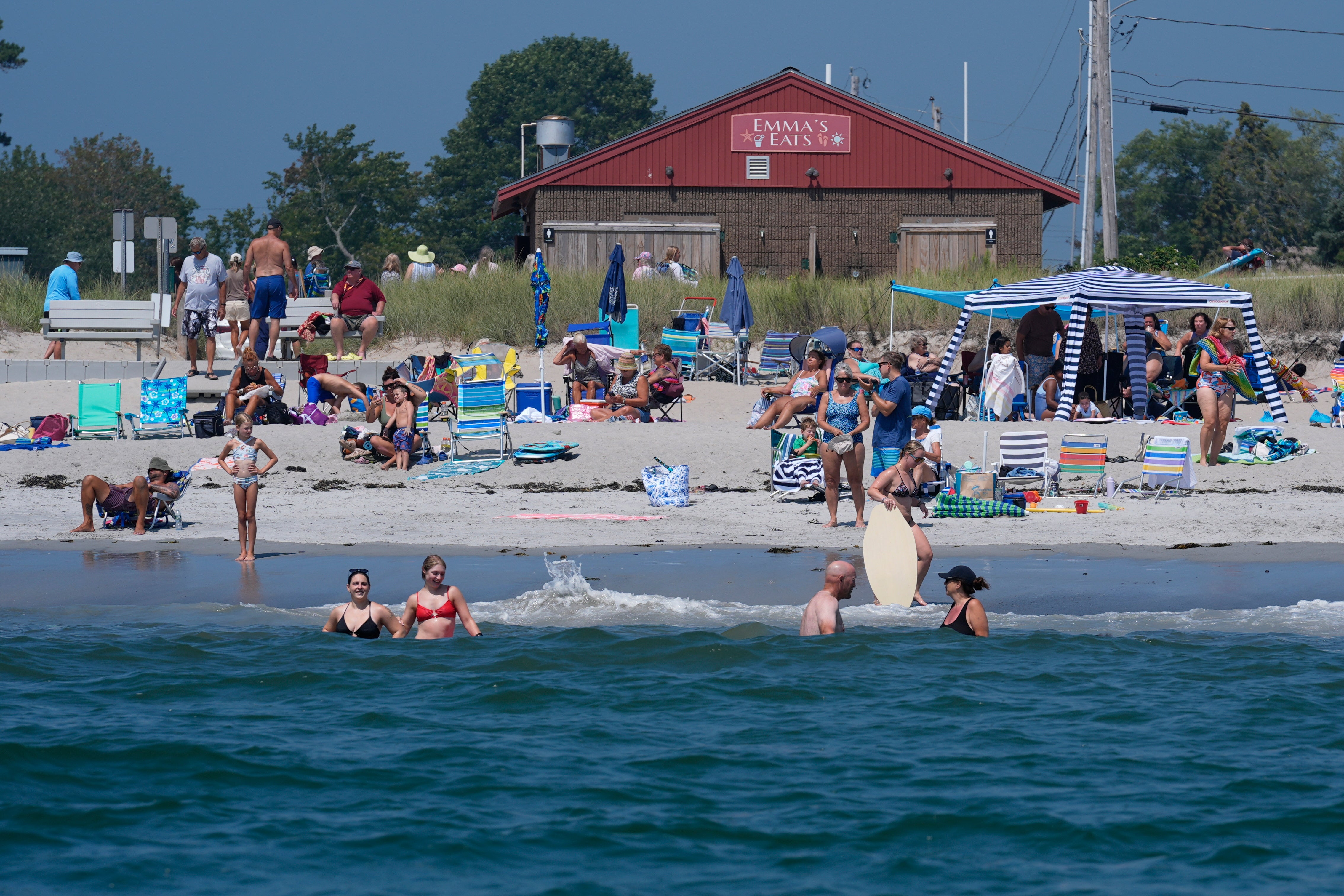 Visitors enjoy the summer weather not far from recent sightings of white sharks, Wednesday, Aug. 13, 2025, in Scarborough, Maine. (AP Photo/Robert F. Bukaty)