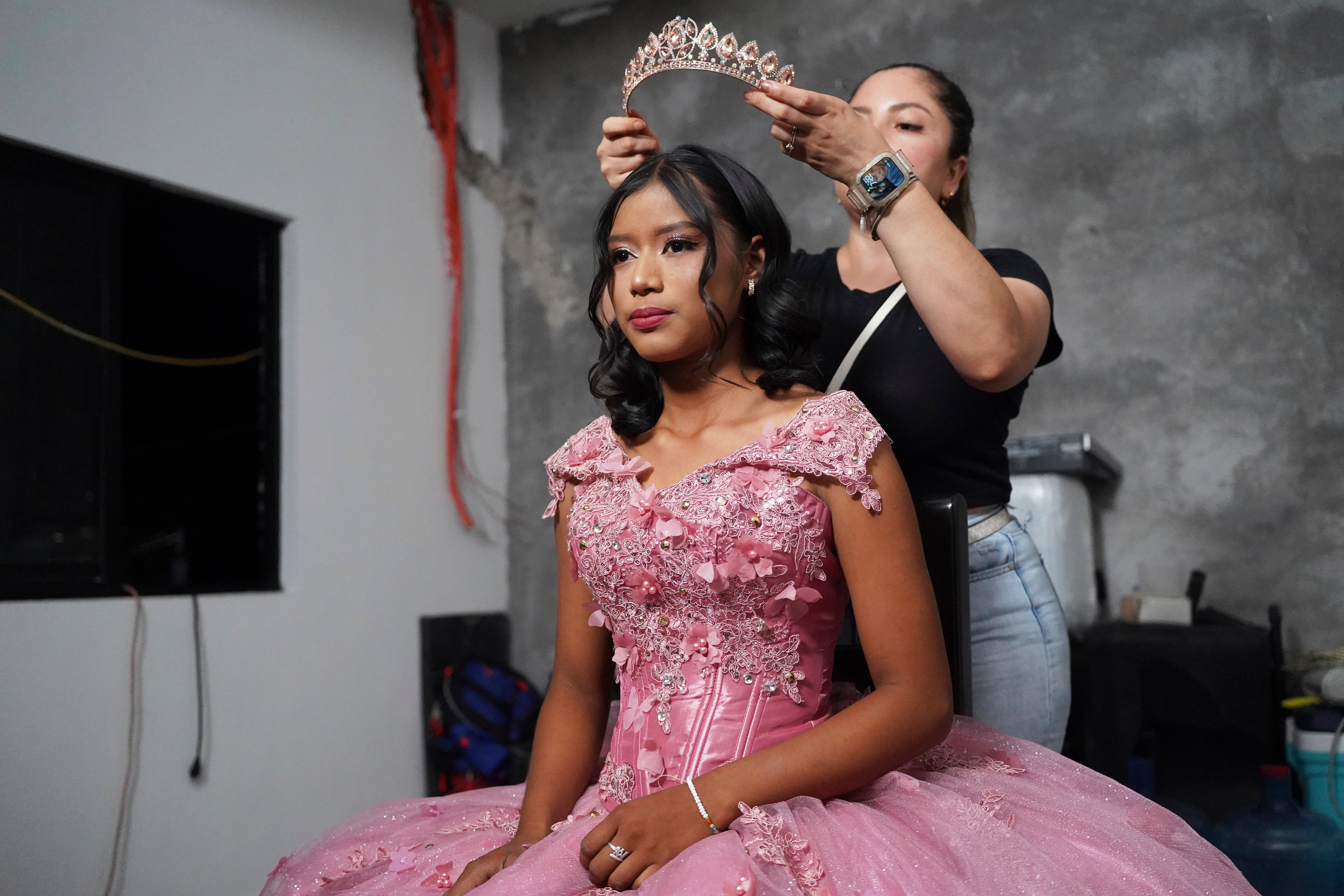 A stylist prepares Isela Santiago Morales for her 15th birthday party, organized by the community after her father's social media appeal drew support following her first sparsely attended celebration, in Axtla de Terrazas, Mexico, Saturday, Aug. 23, 2025. (AP Photo/Mauricio Palos)