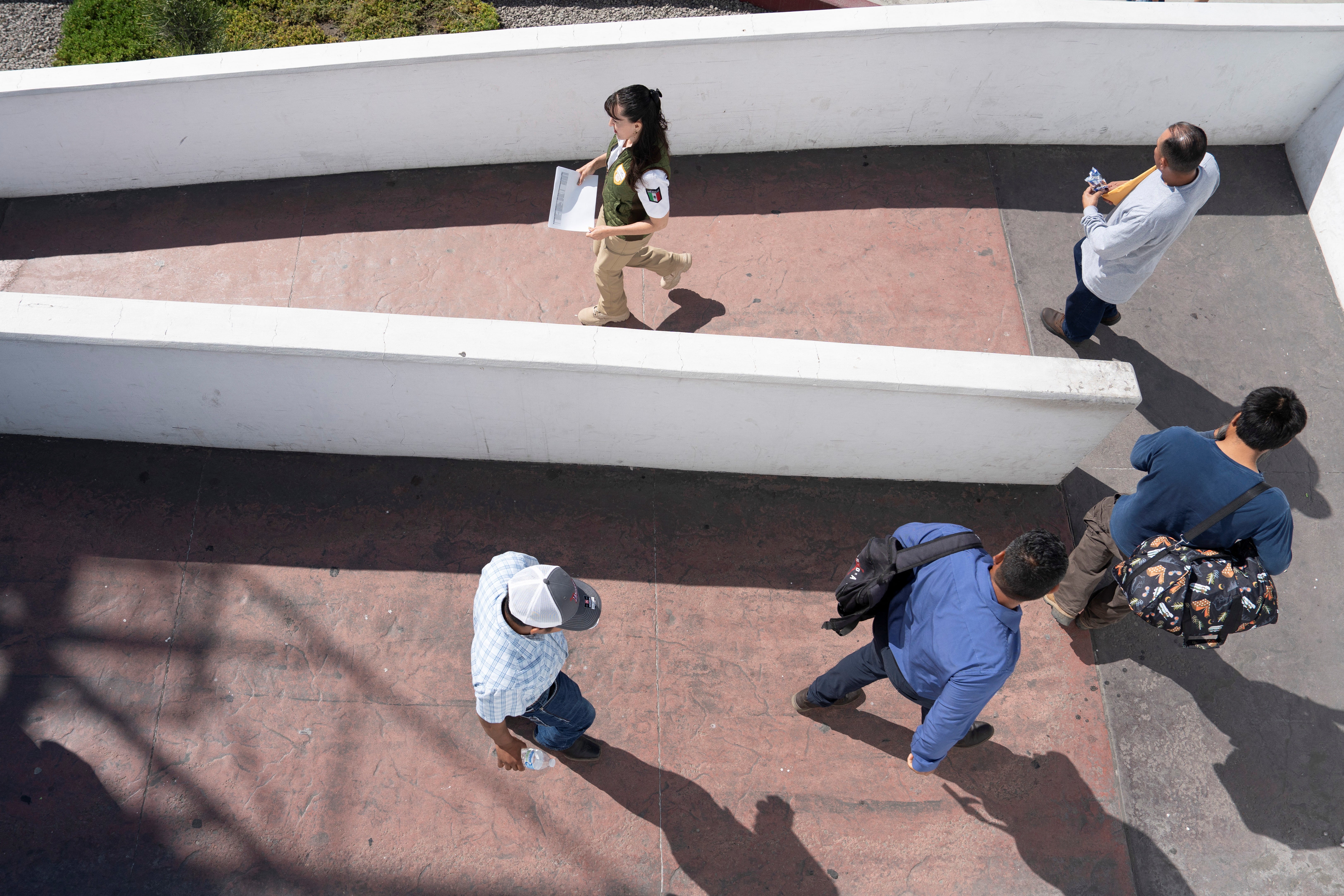 Mexican migrants, recently deported after being apprehended in US Immigration and Customs Enforcement (ICE) raids, follow an agent of Mexico's National Migration Institute