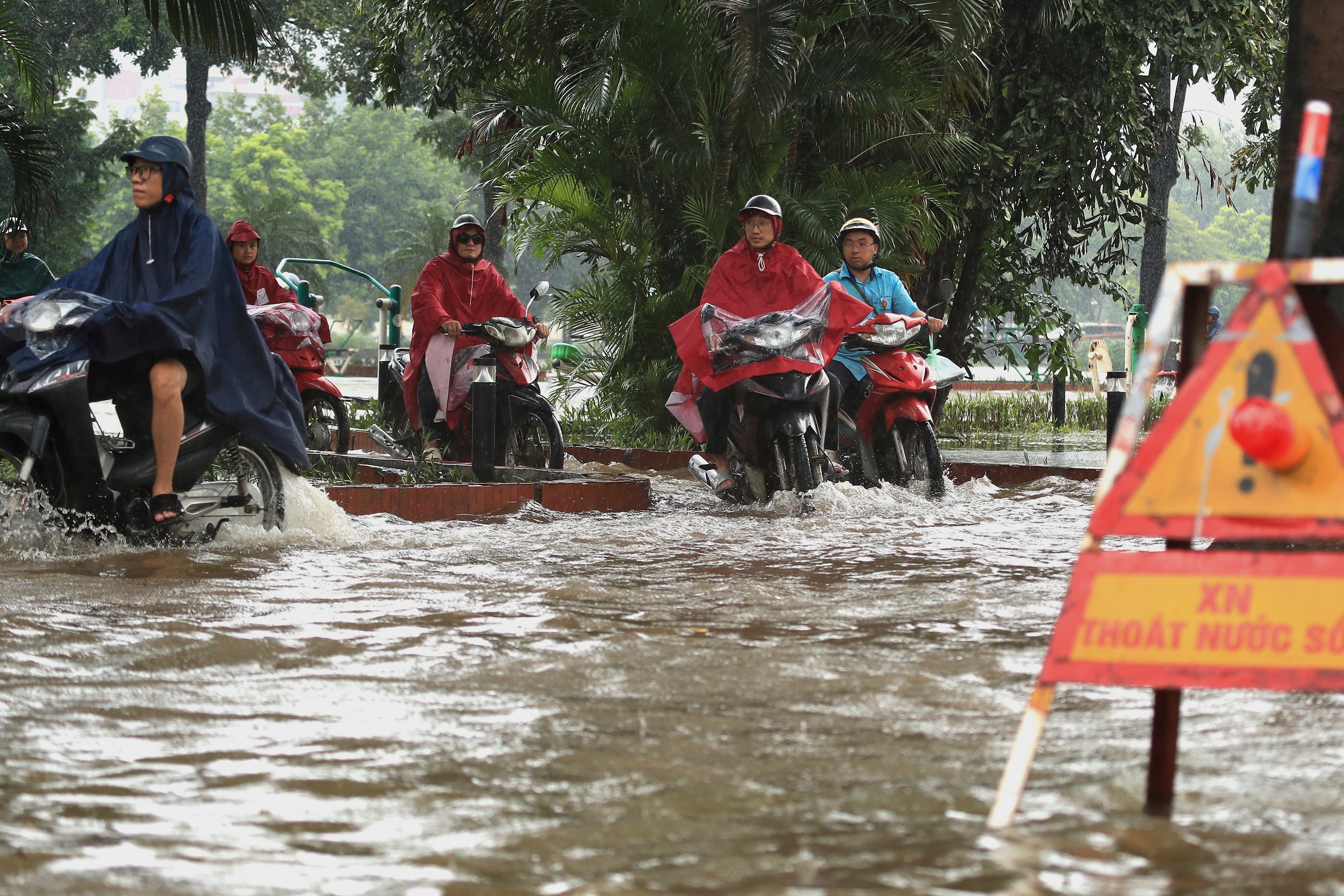 People drive motorcycles on a flooded street in Hanoi, Vietnam