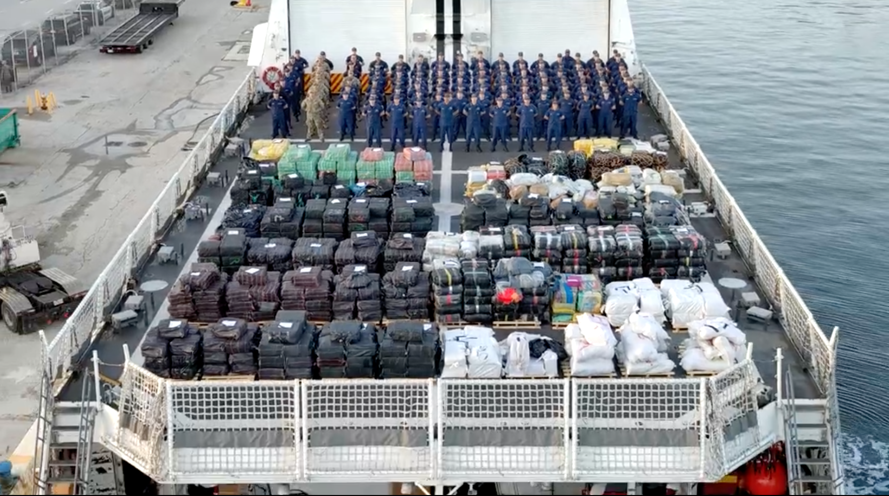 Members of the U.S. Coast Guard stand on the deck of the cutter Hamilton with a record-breaking haul of cocaine and marijuana seized from suspected drug-trafficking ships between mid-June and mid-August of 2025