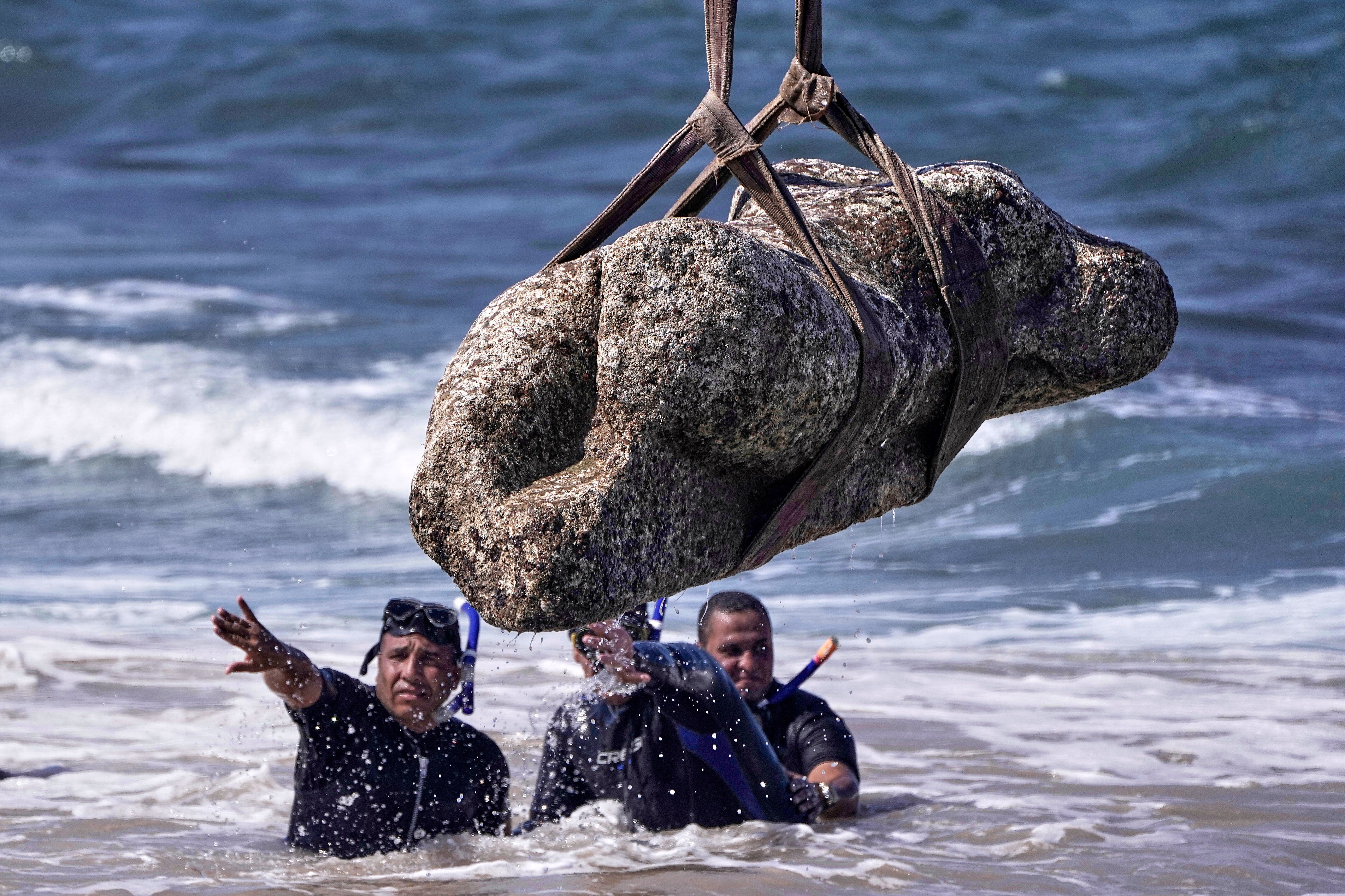 Divers monitor one of the ancient artefacts as it is lifted out of the water in Abu Qir Bay