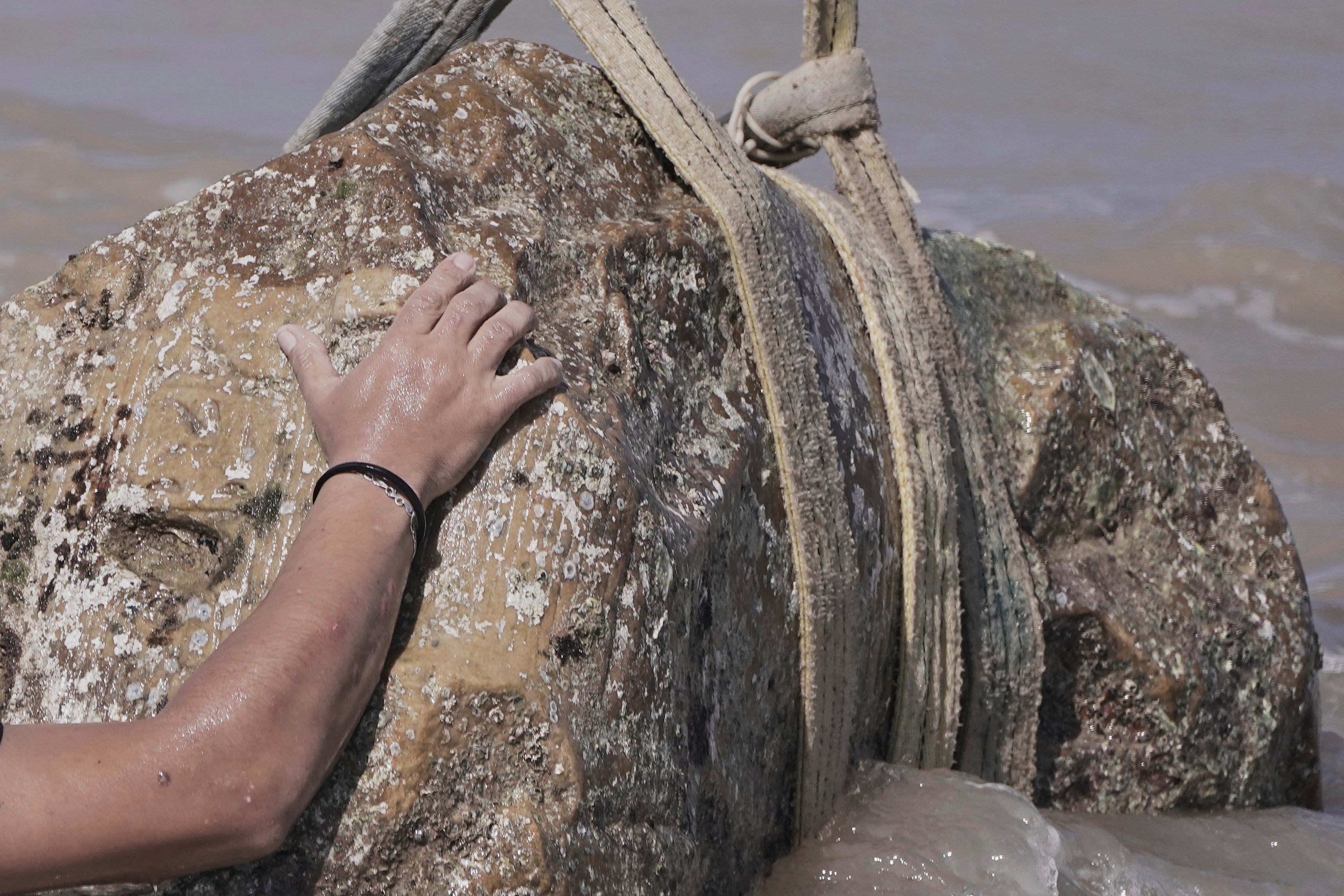 A diver prepares to lift an unknown statue out of the water in Abu Qir Bay