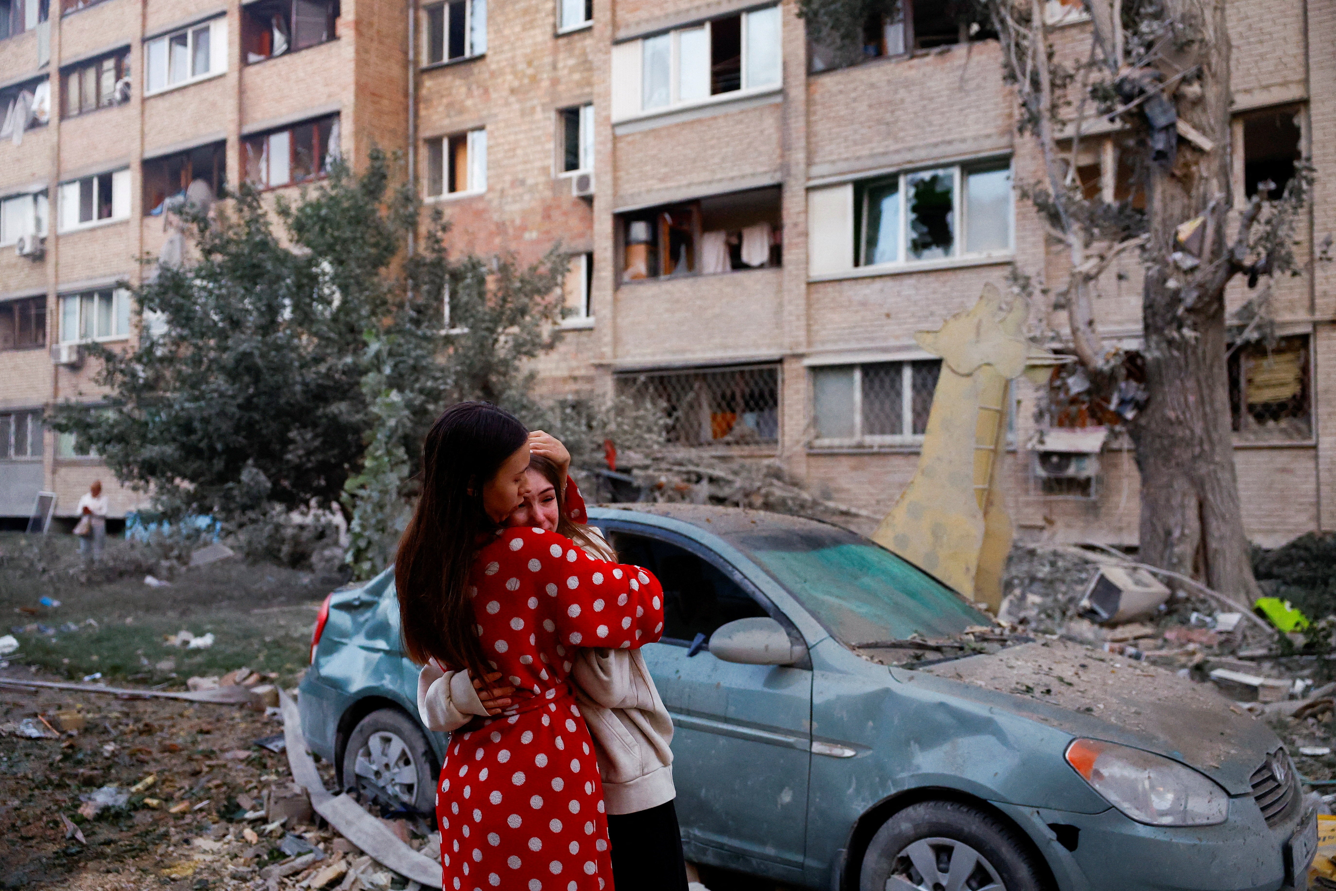 Woman stand at the site of a building attacked by Russian forces in Kyiv