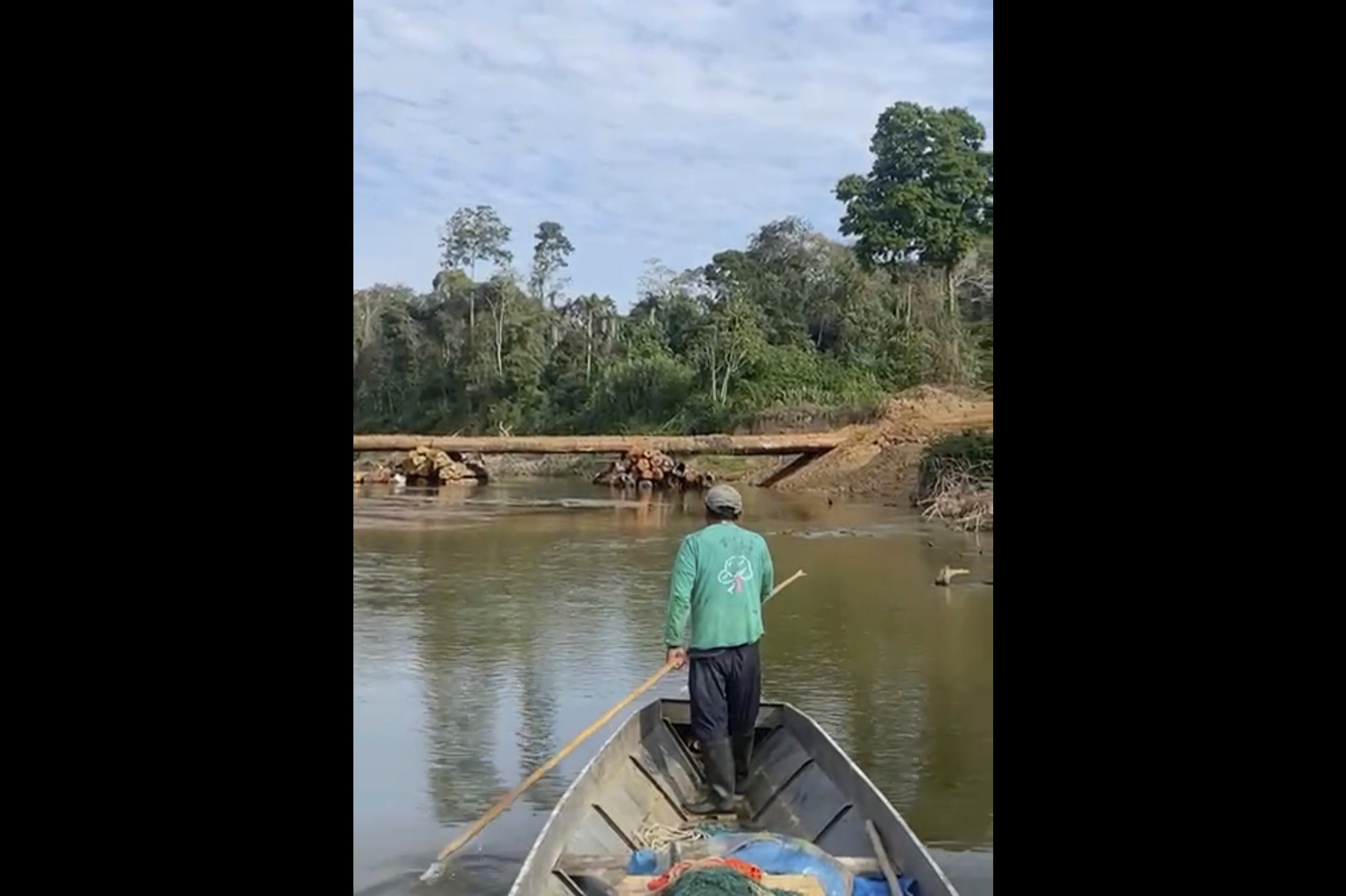 Dabi Nishida, of the Yine Indigenous group, maneuvers a boat near a bridge built by the company Maderera Canales Tahuamanu along the Tahuamanu River