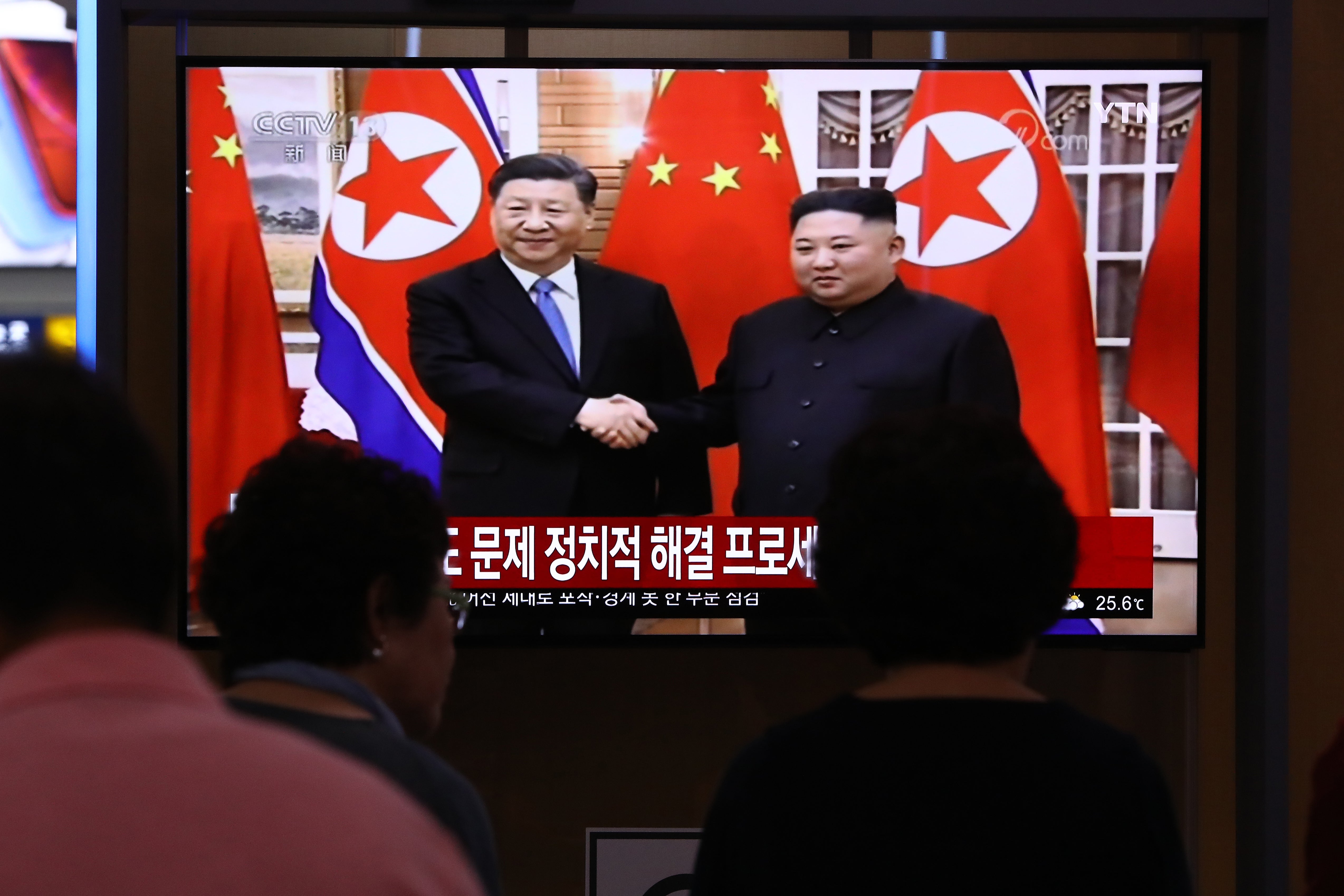 A TV screen shows North Korean leader Kim Jong Un shaking hands with Chinese president Xi Jinping at the Seoul Railway Station on 20 June 2019