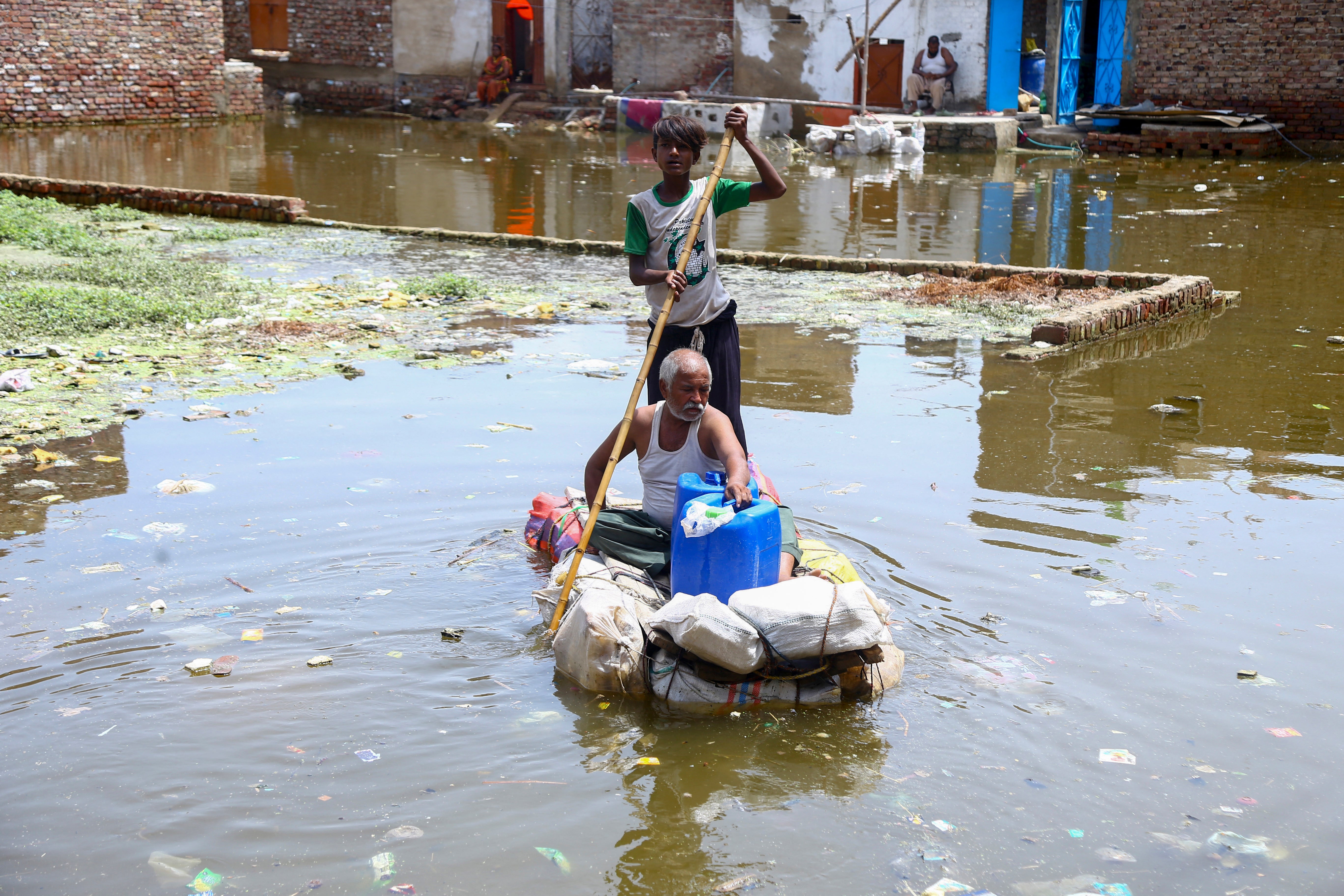 People wade through floodwaters in a residential area following heavy monsoon rain in Hyderabad, Pakistan