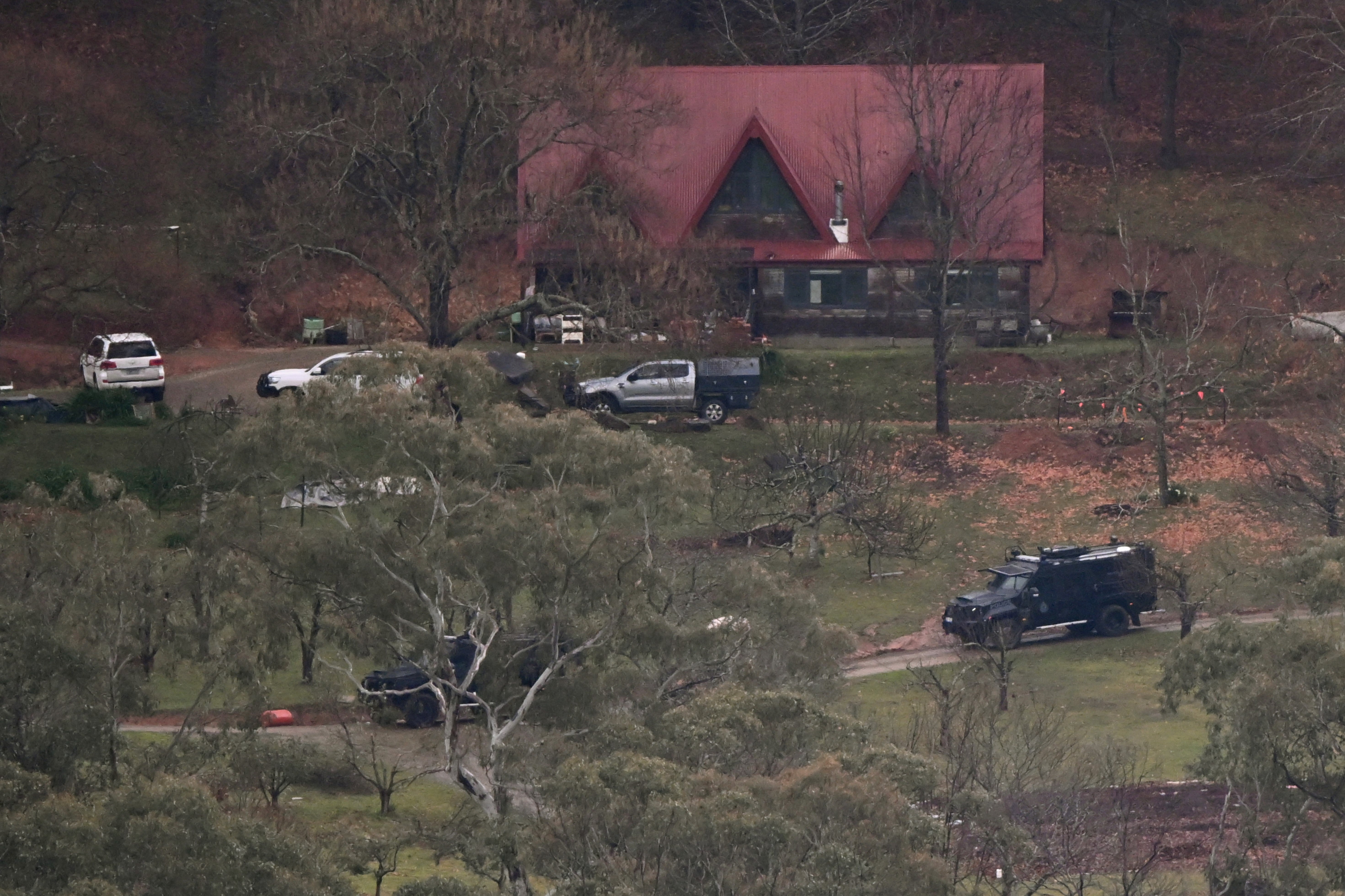 Heavily armed police search buildings while looking for a fugitive linked to the murder of two police officers, in Porepunkah on 28 August 2025