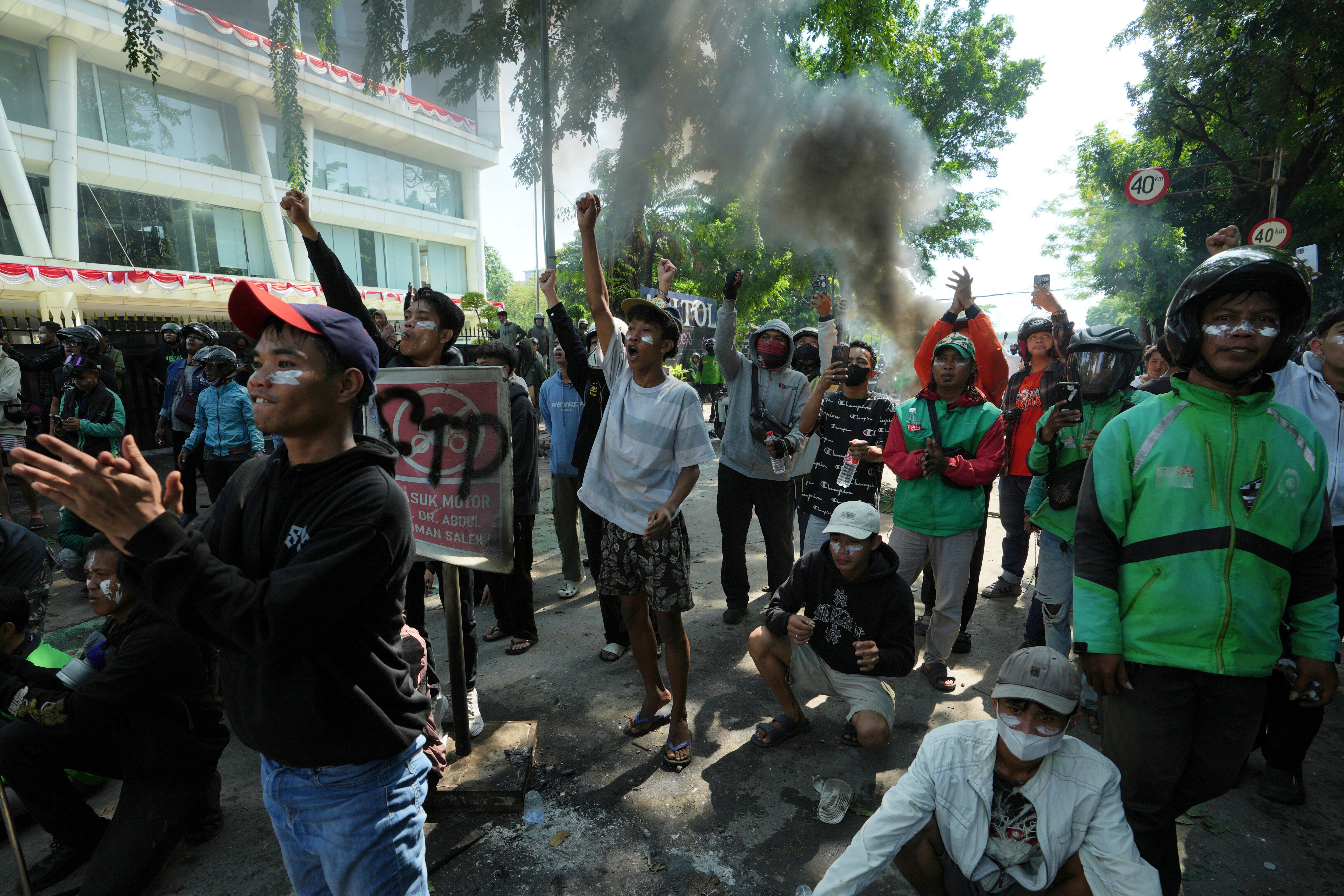 People shout slogans during a protest following the death of a ride-hailing driver who was run over by a police armoured car