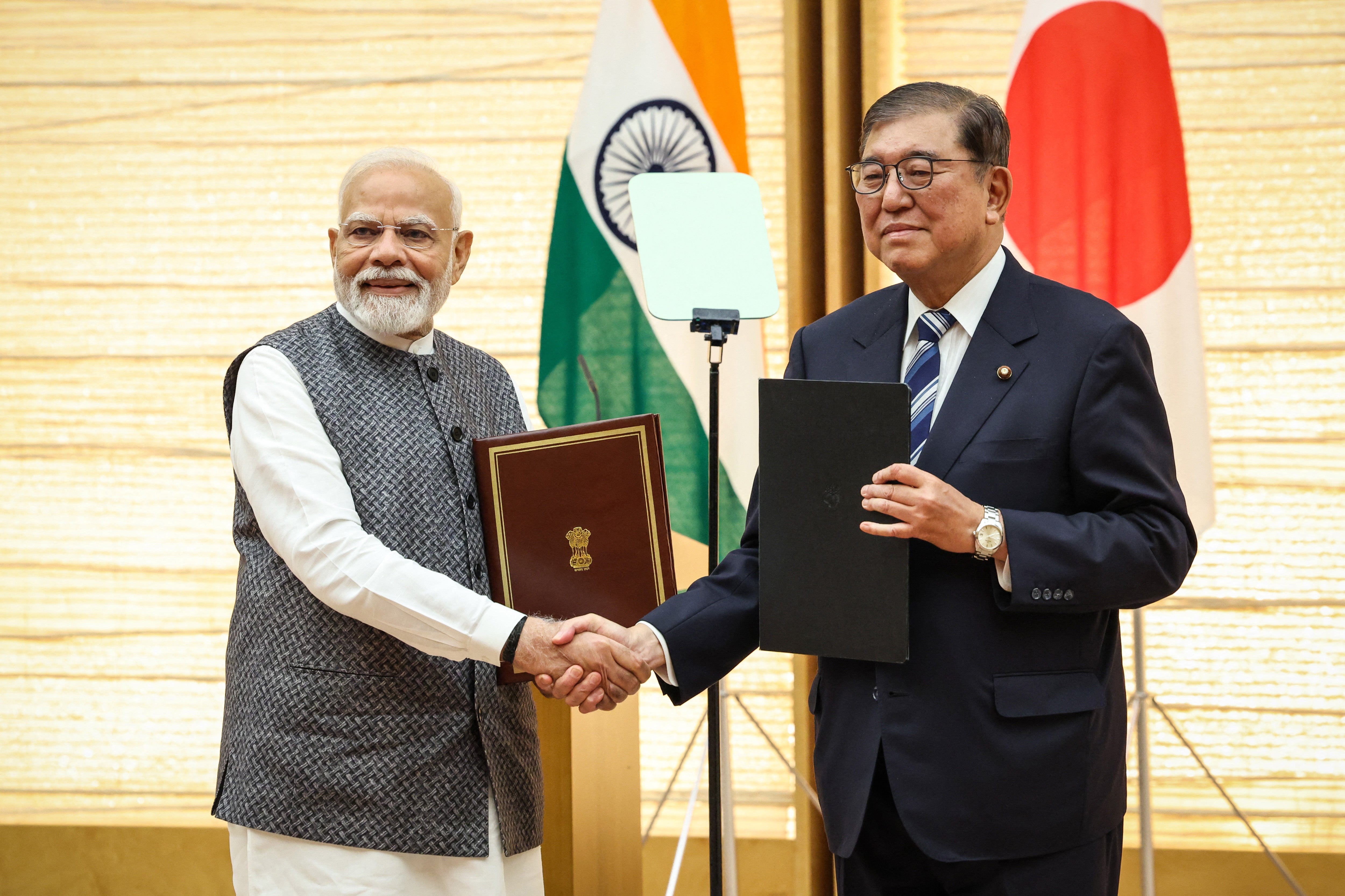 India's Prime Minister Narendra Modi (L) and Japan's Prime Minister Shigeru Ishiba shake hands during a joint press conference in Tokyo on August 29, 2025