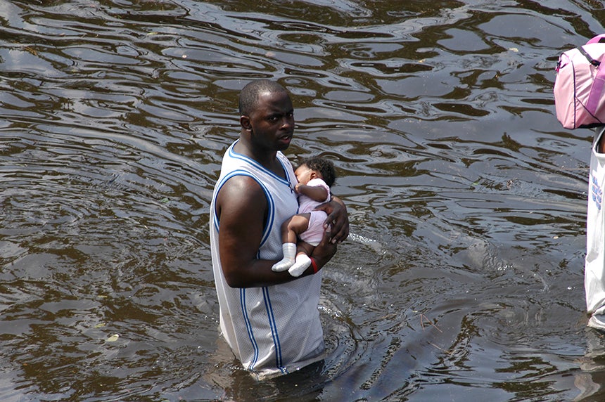A man carries a baby through the flooded streets of New Orleans