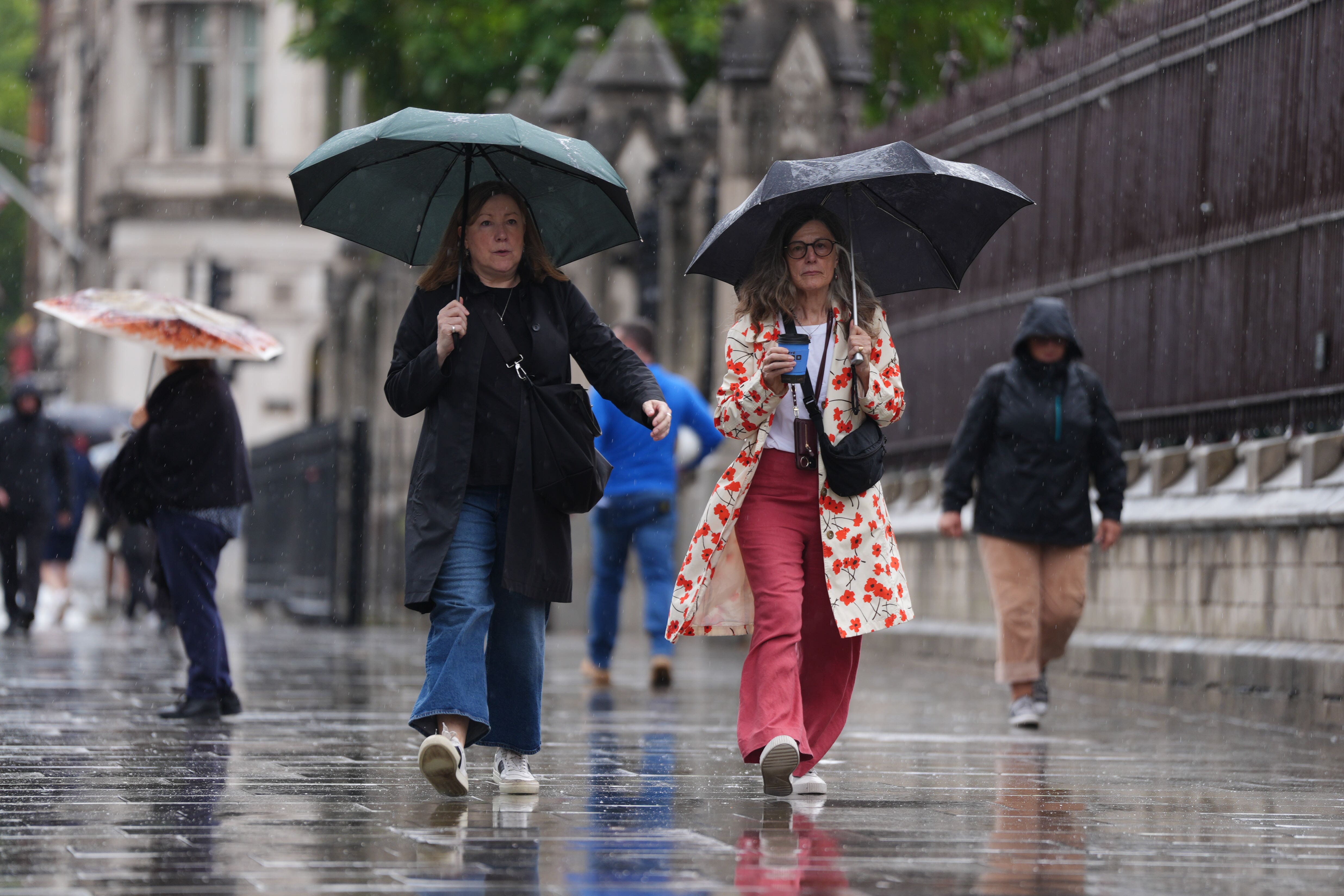 People under umbrellas during a downpour in Westminster on Friday (Ben Whitley/PA)