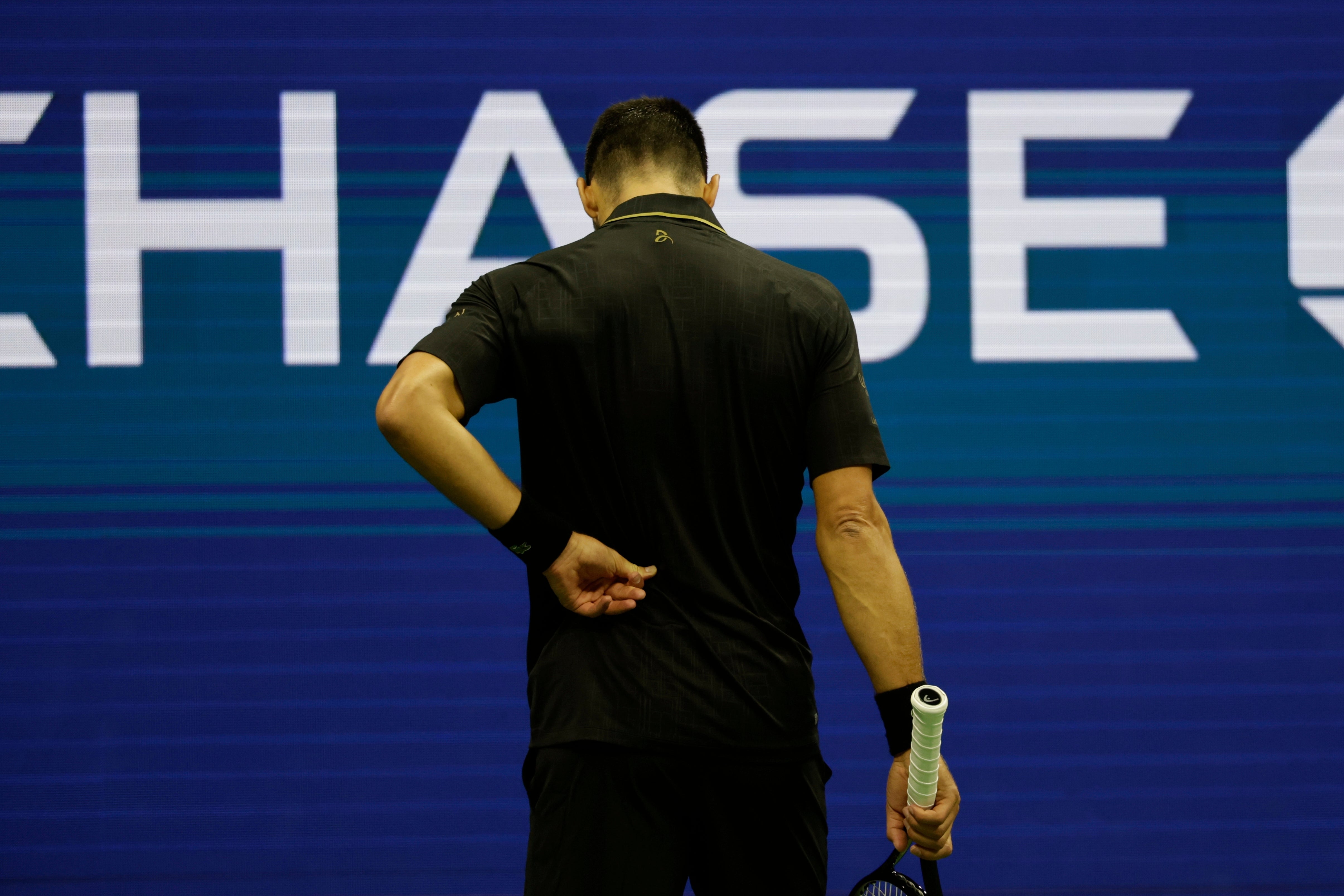 Novak Djokovic holds his back (Adam Hunger/AP)