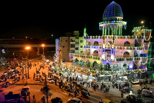 <p>Commuters ride past a mosque illuminated ahead of Eid-e-Milad-un-Nabi, which commemorates the birth anniversary of Prophet Mohammed in Karachi on August 30, 2025</p>
