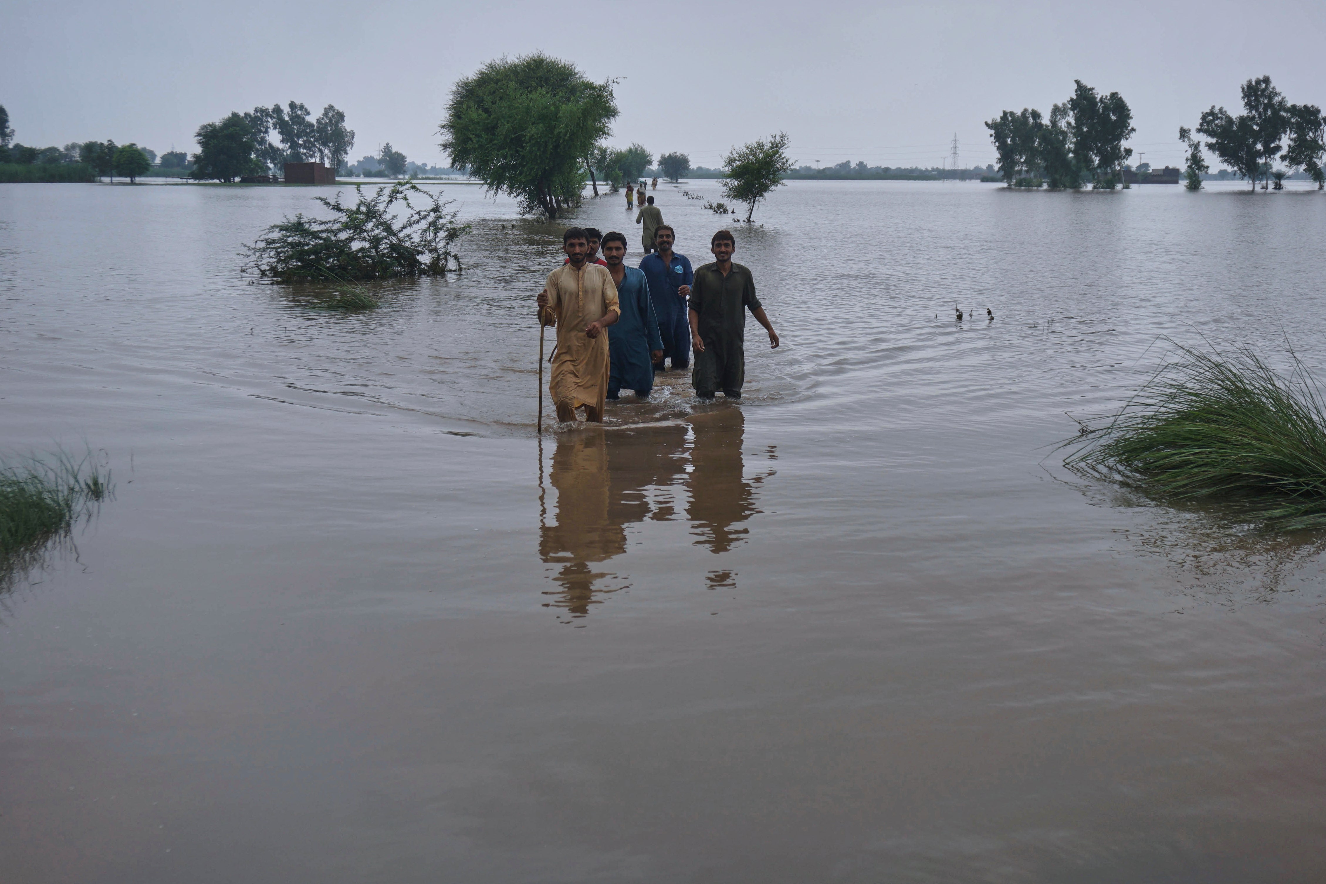 Villagers wade through a flooded area in Pindi Bhattian, Pakistan, on 31 August 2025