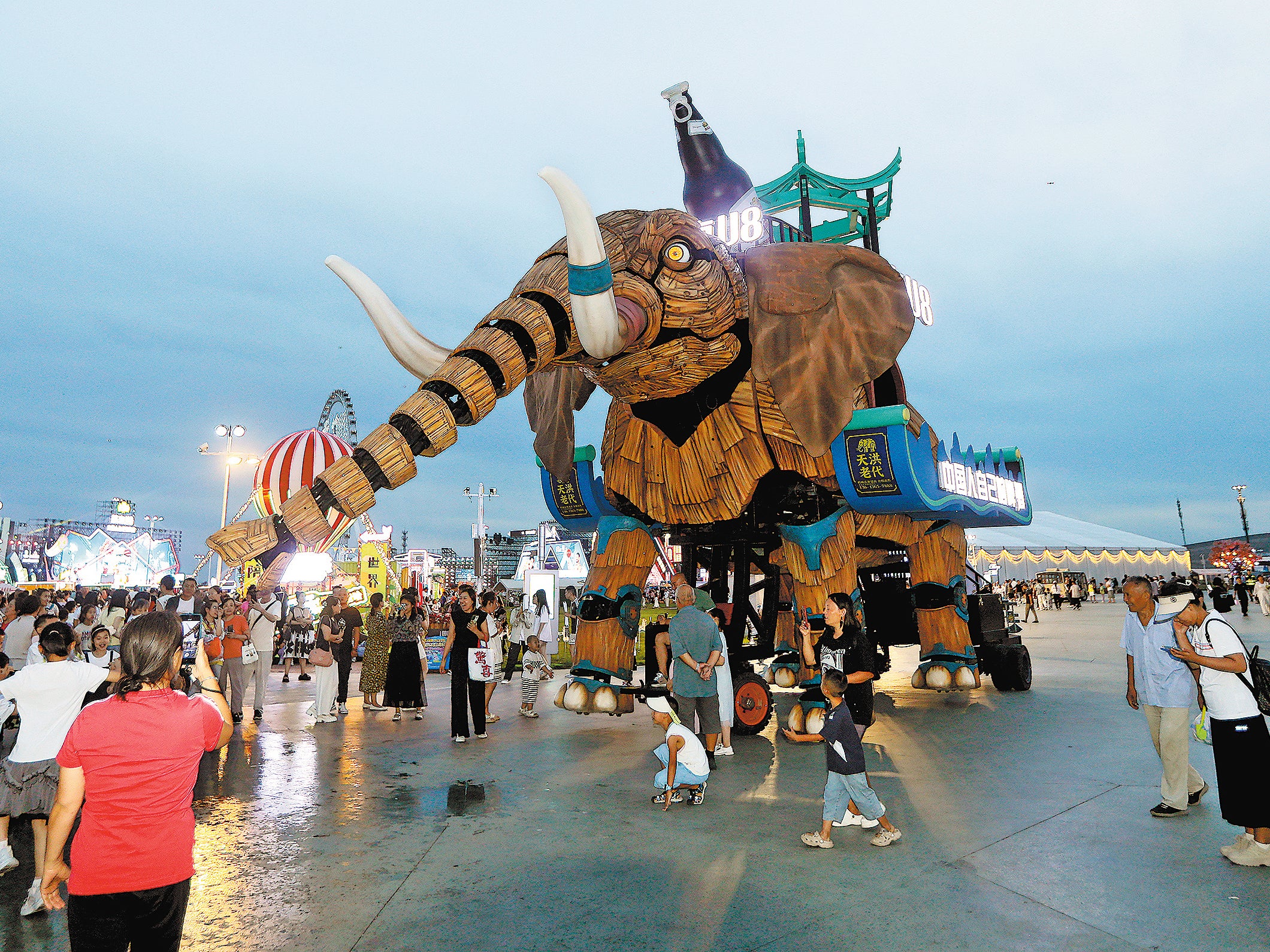 People watch and take pictures of a mechanical elephant during the 23rd Harbin International Beer Festival in Harbin, Heilongjiang province, on 9 August