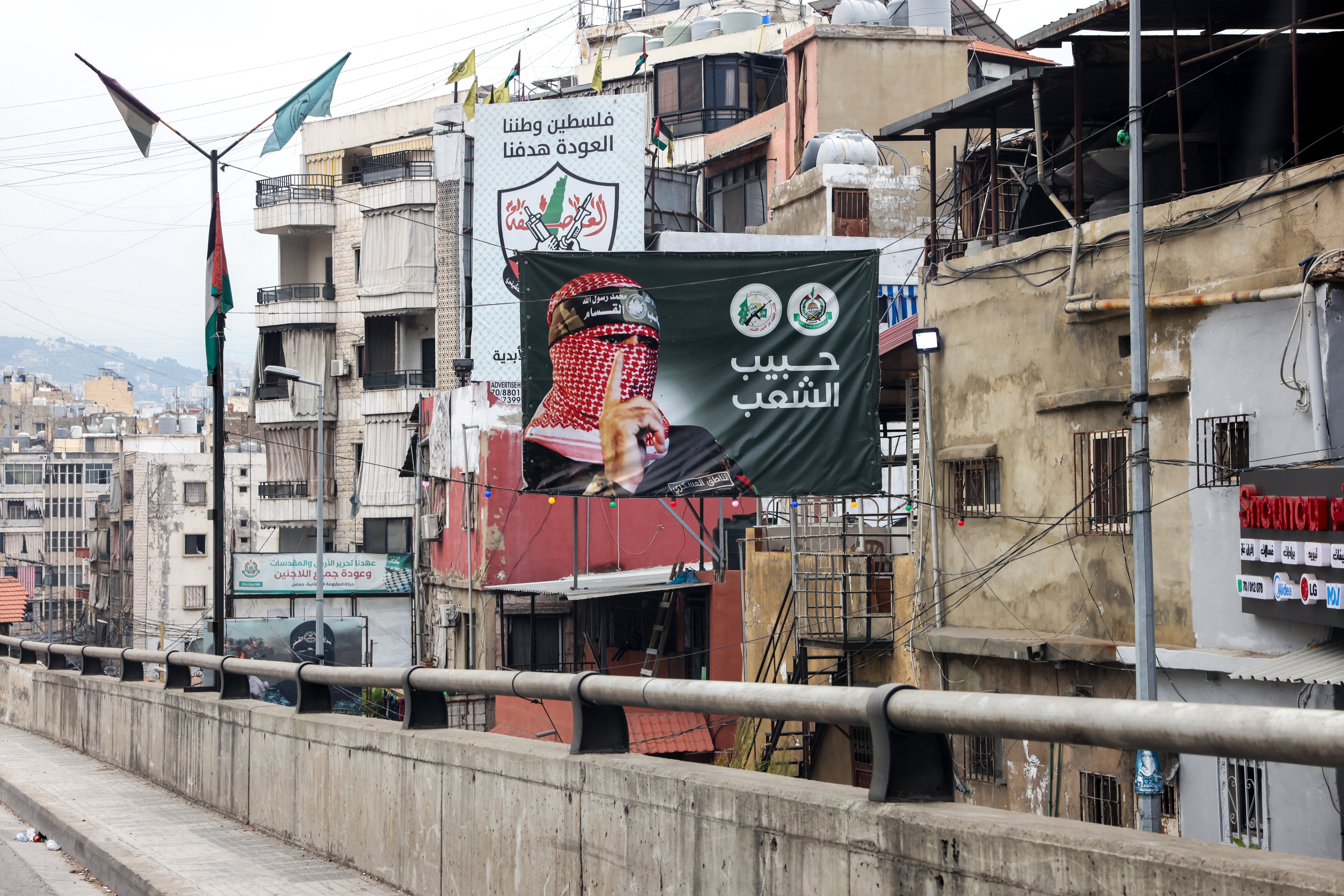 A poster showing Abu Obeida, the spokesman of Hamas' Ezzedine Al-Qassam Brigades, stands in a street in Beirut's southern suburb on June 21, 2024