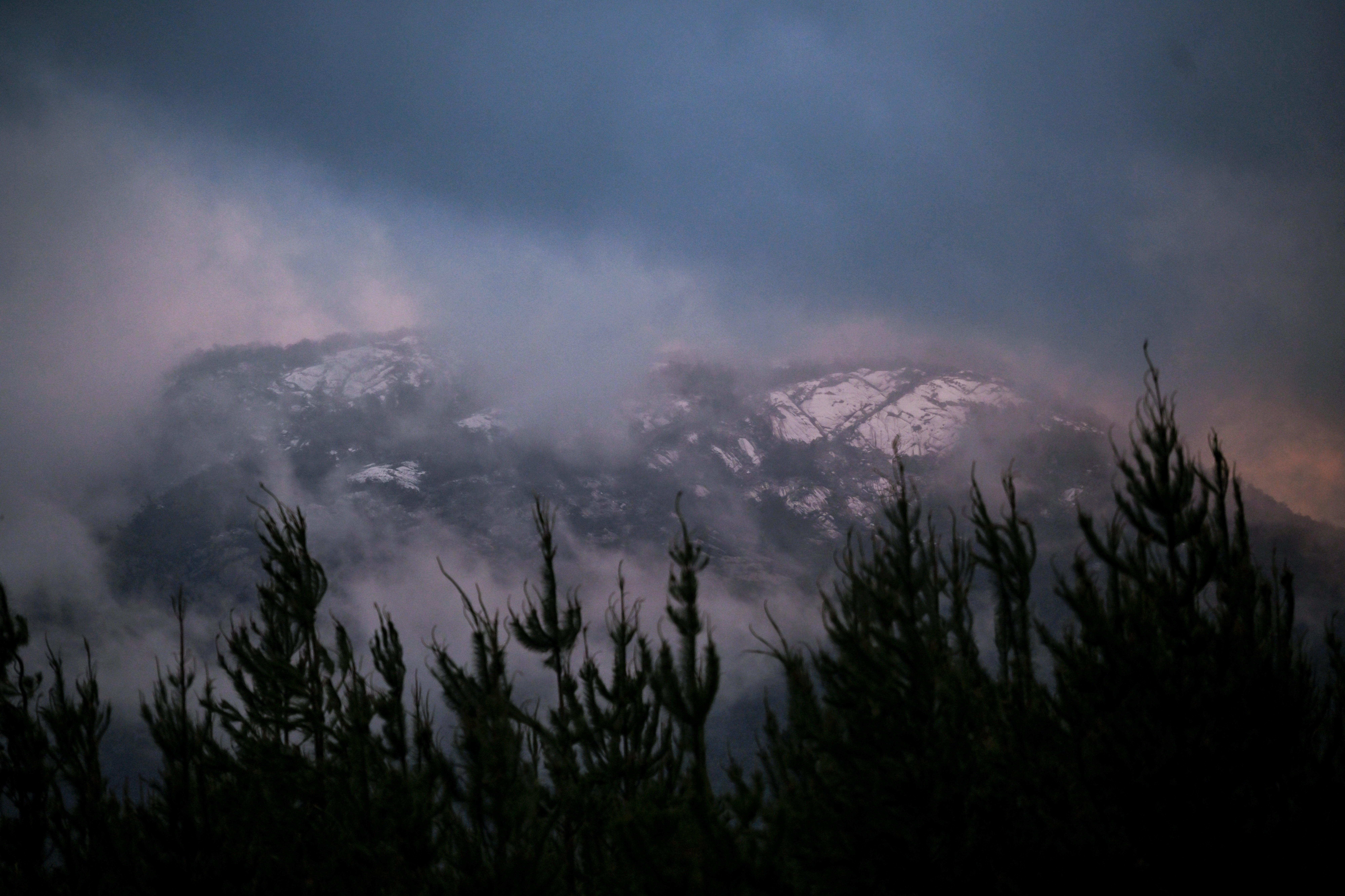 Snow settles on the hills in the area where police are searching for a fugitive linked to the murder of two police officers in Porepunkah on 29 August 2025