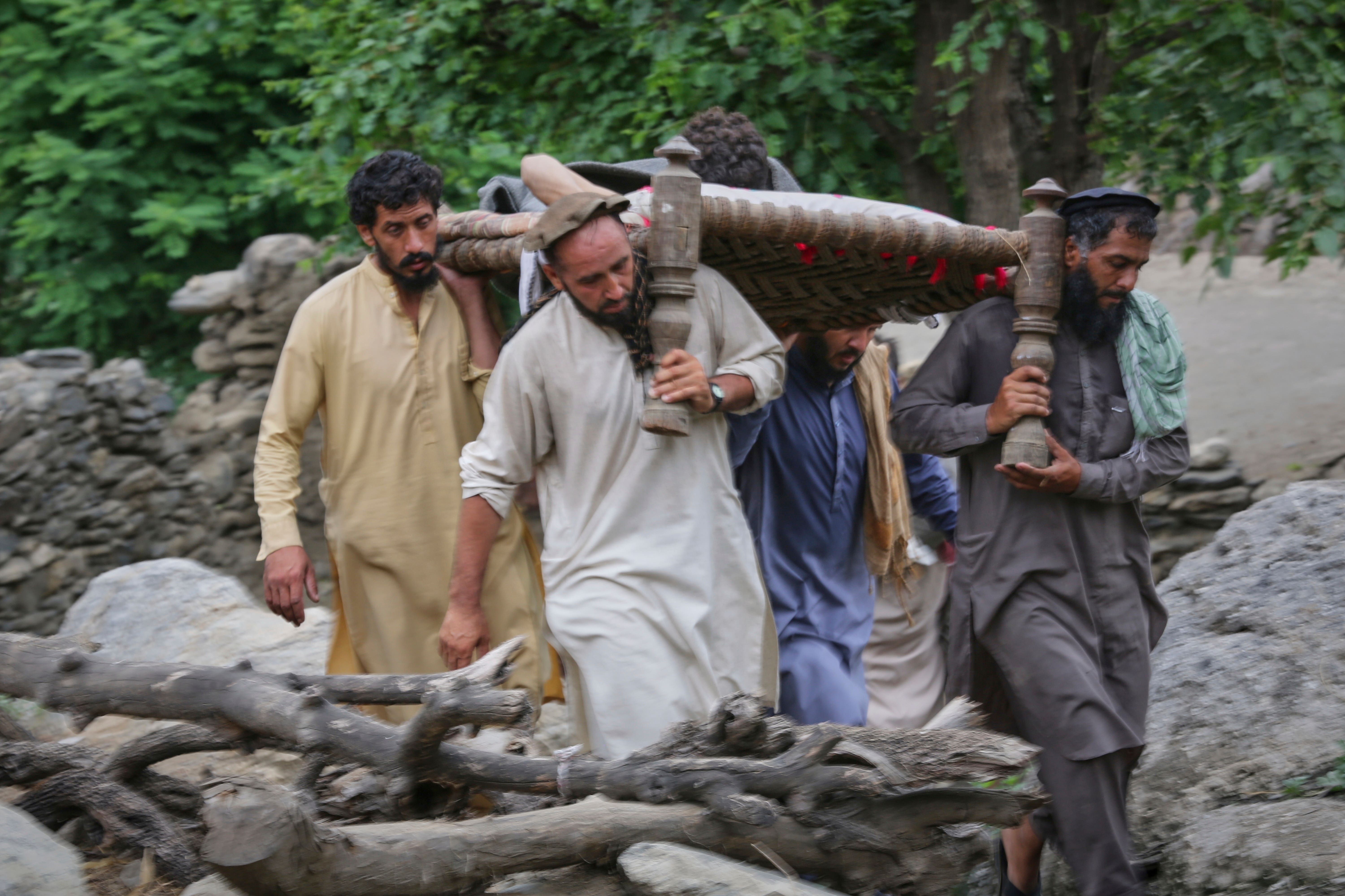 An injured person is carried on a bed to a military helicopter for evacuation in a village in Mazar Dara, Kunar province (Wahidullah Kakar/AP)