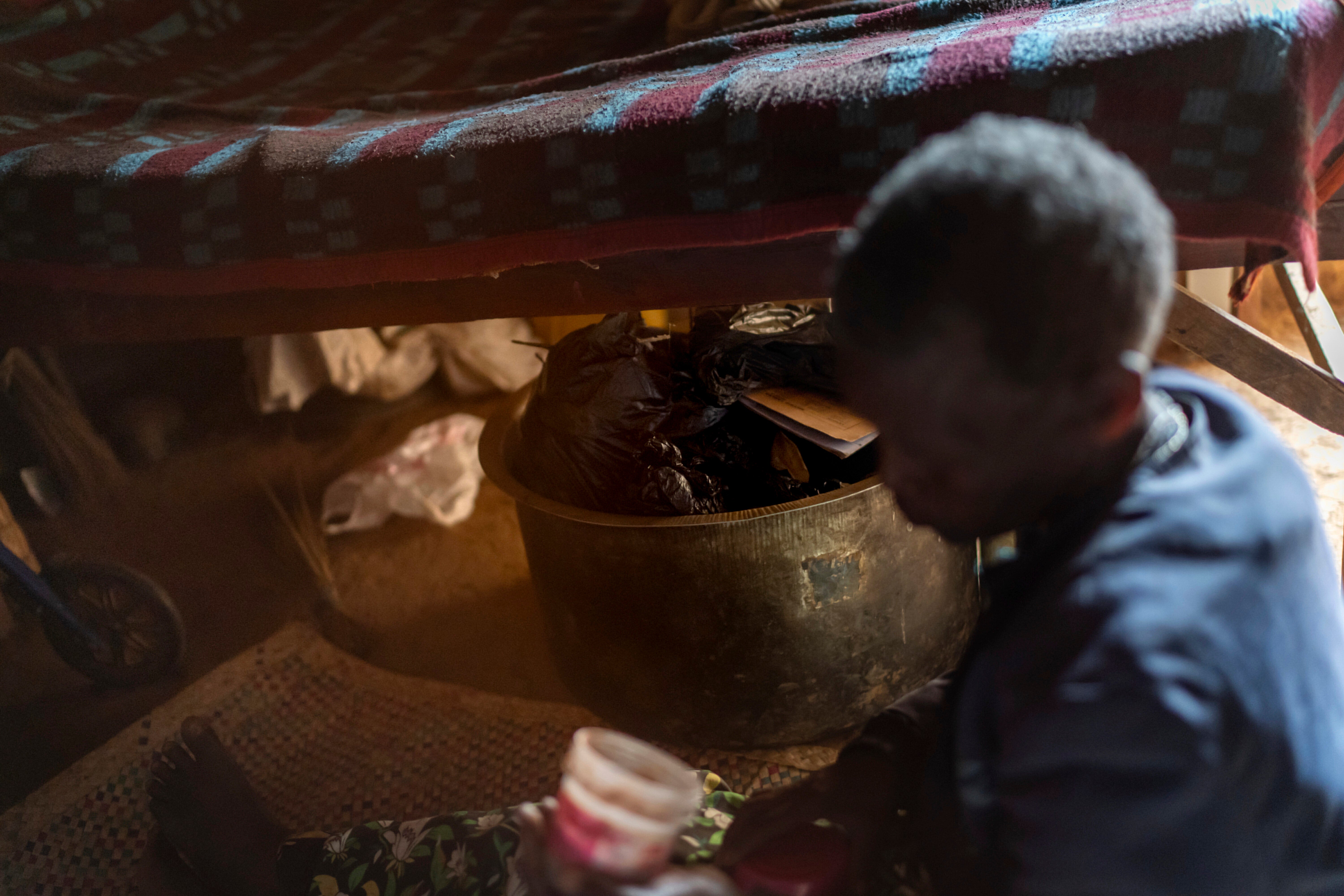 A metal basket sits under the bed of witch doctor Fredianah Tibeijuka, containing the tools of her trade