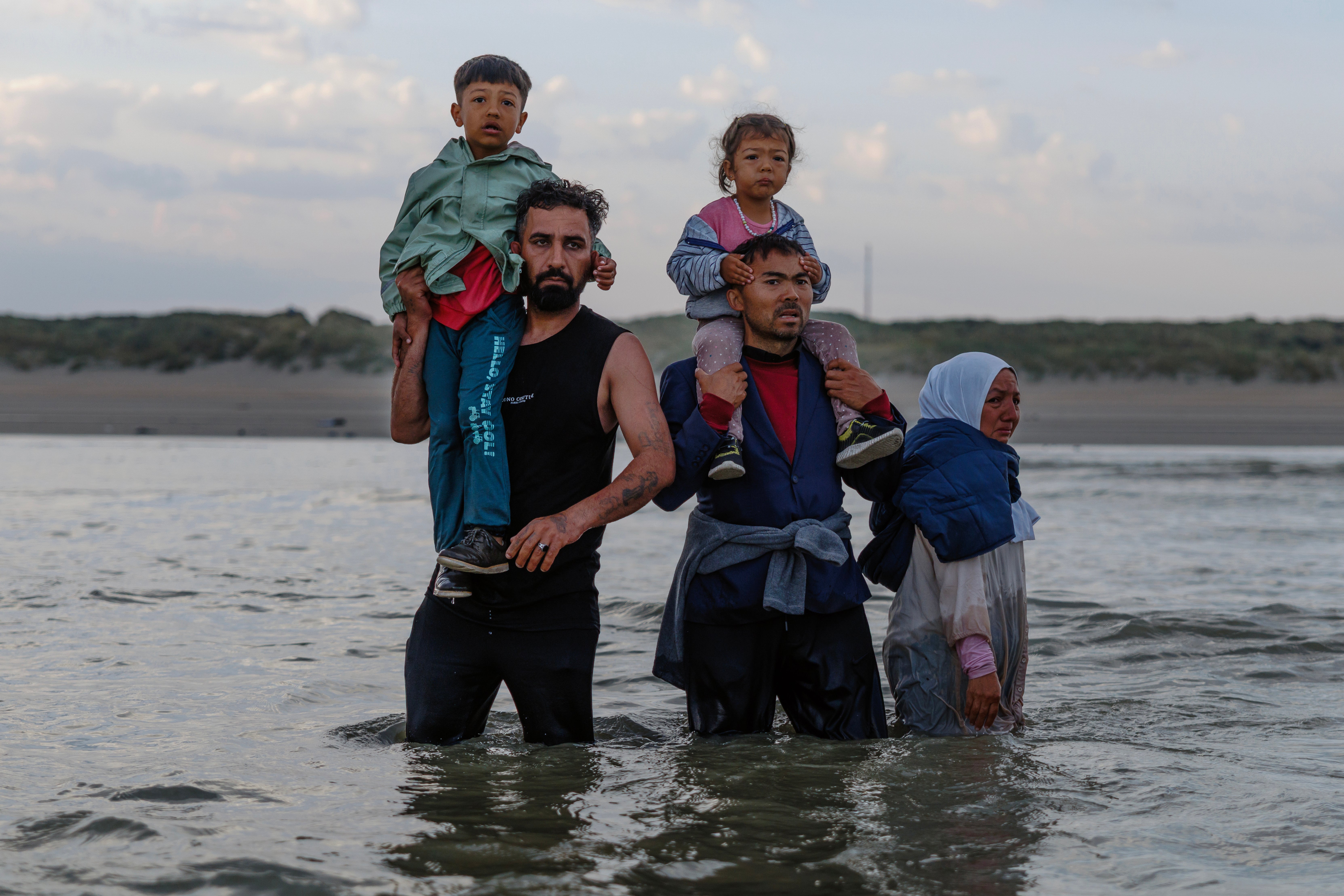 Migrants stand in the sea dejected after failing to board a small boat in Gravelines, France
