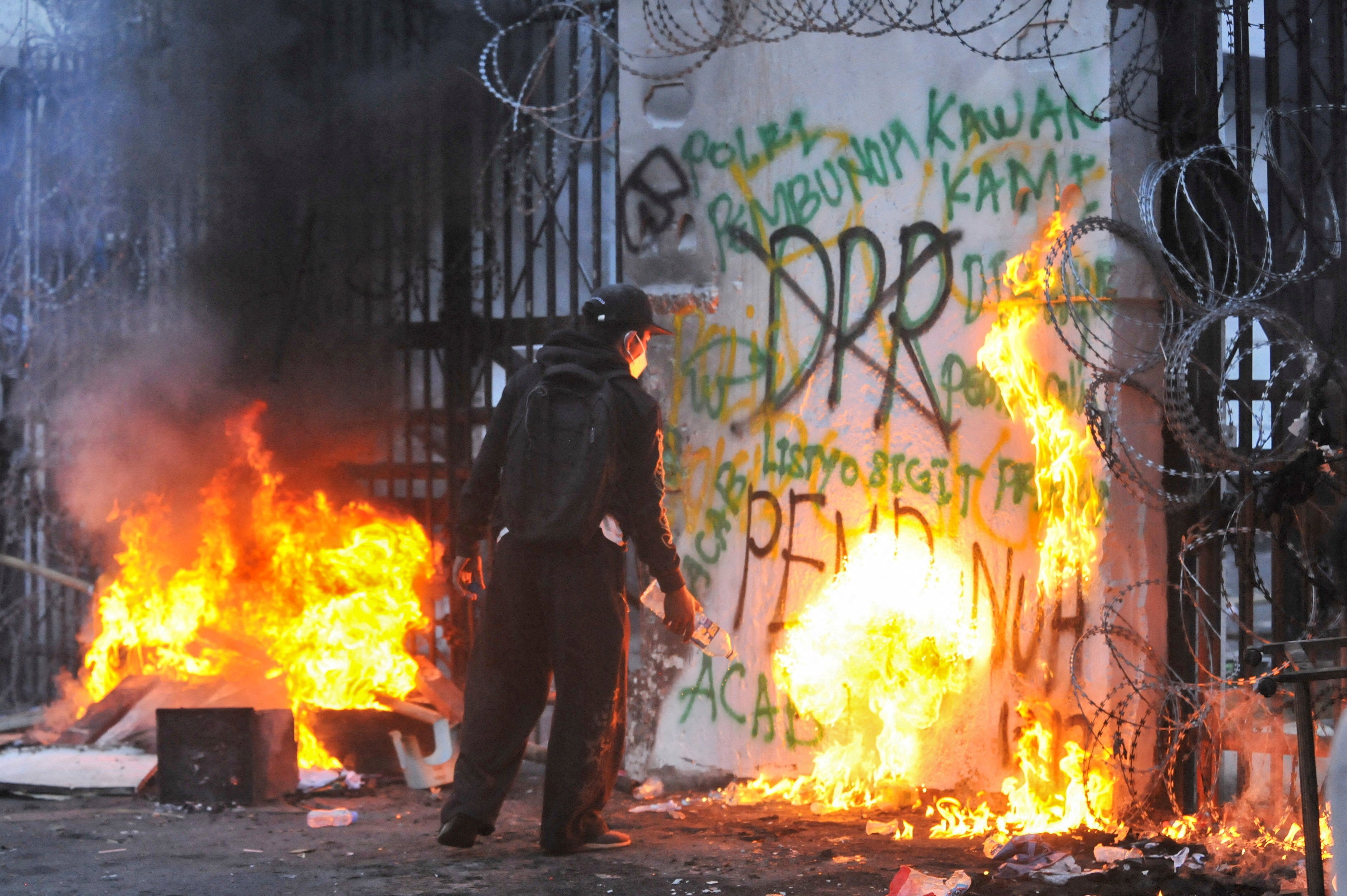 A protester sets fire to the gate of the regional parliament building during a protest against the government's spending priorities, such as enhanced perks for lawmakers, in Bandung, West Java province
