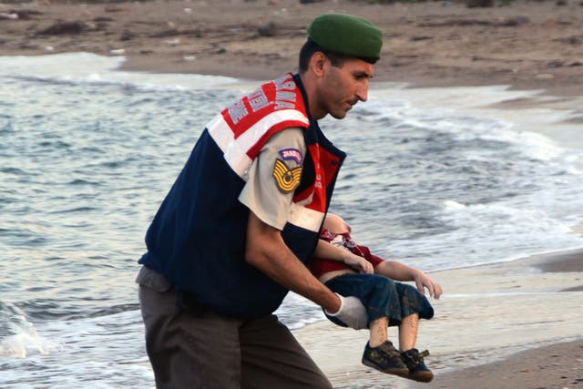 <p>An officer carries Alan’s body away after he washed up on a beach in Turkey</p>