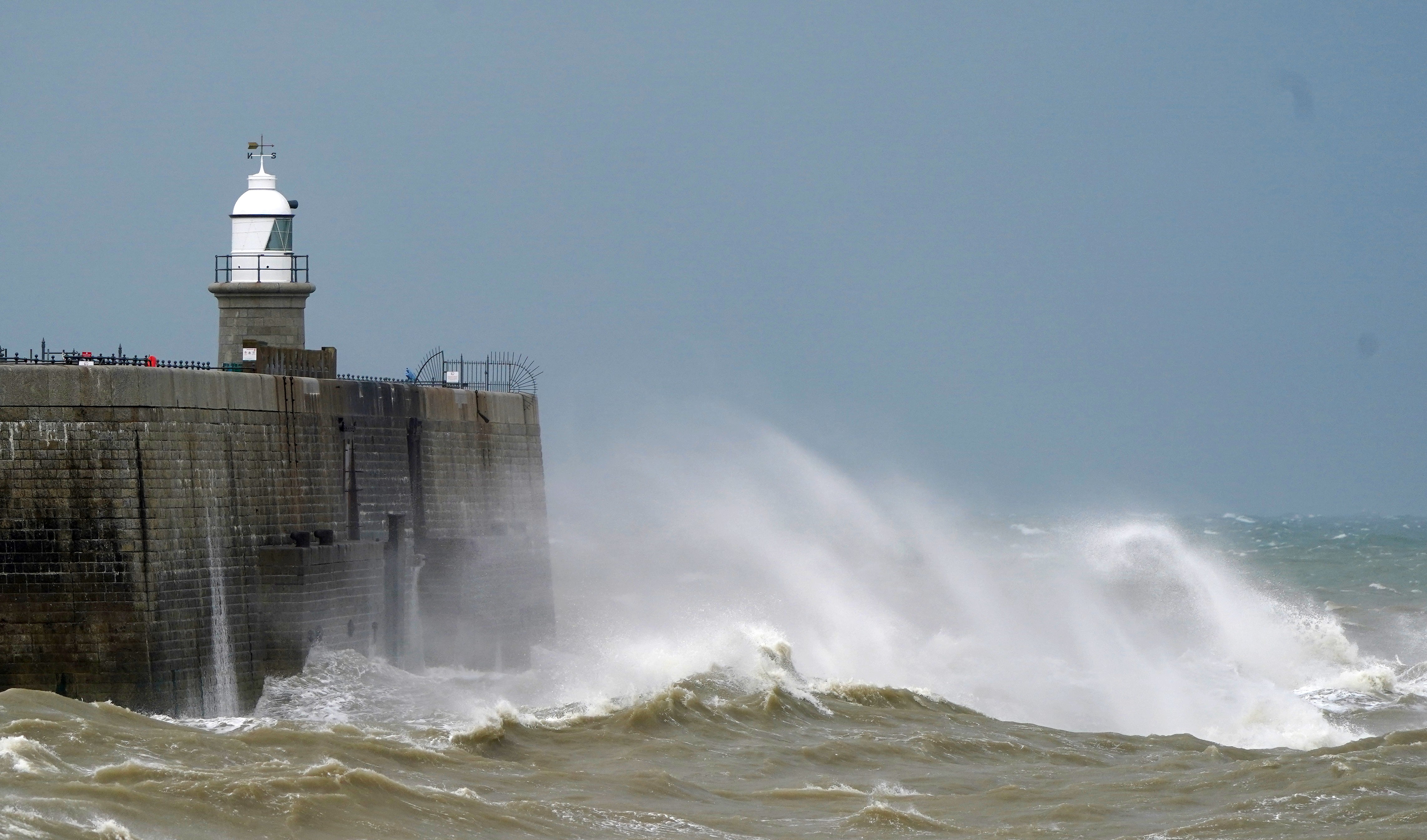 <p>Waves crash over the harbour wall during windy conditions in Folkestone, Kent</p>