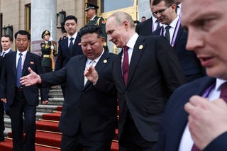 Russian president Vladimir Putin and North Korean leader Kim Jong Un gesture as they leave a reception in Beijing