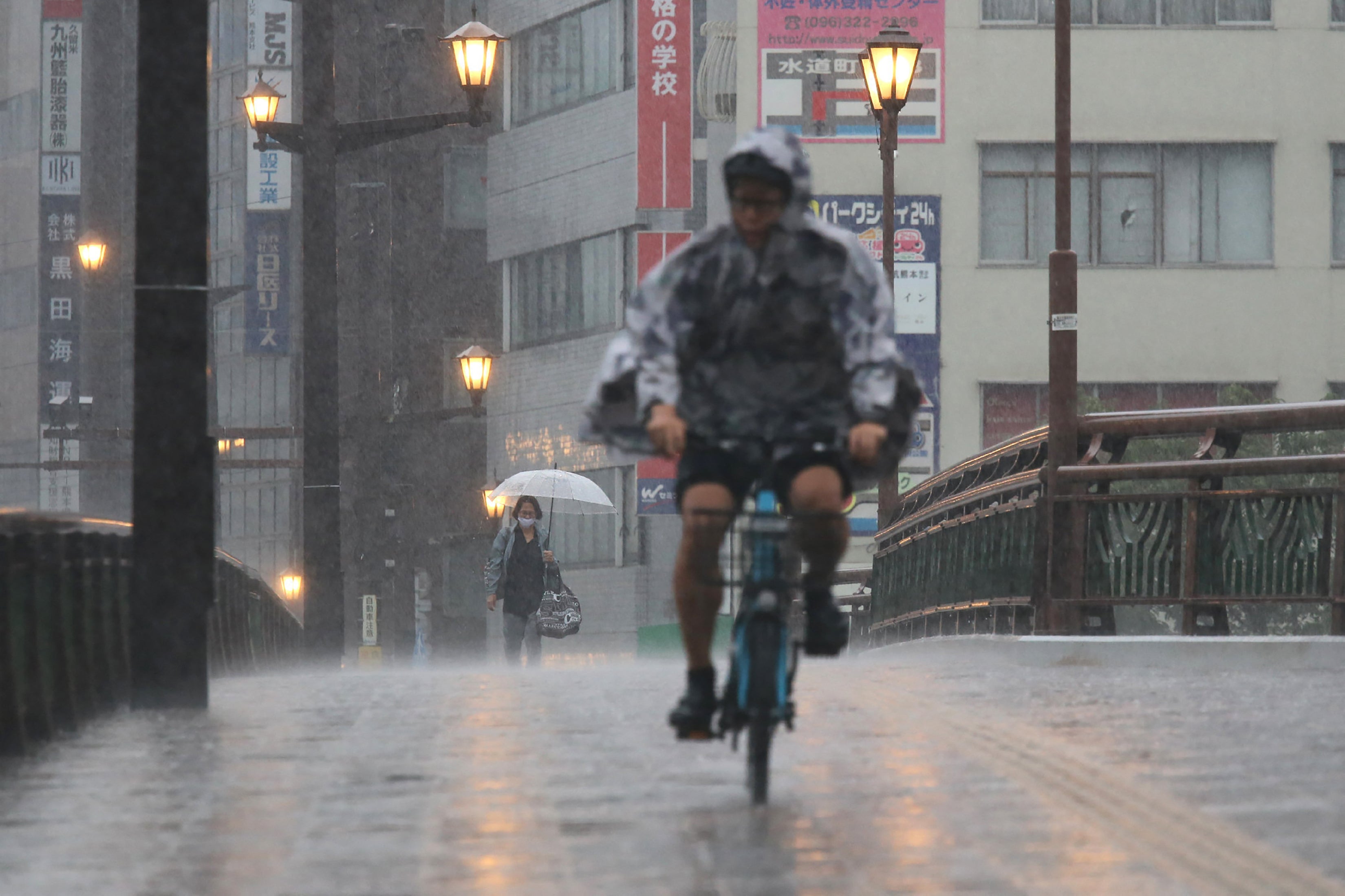 <p>File. People cycle and walk in heavy rain in the city of Kumamoto, Kumamoto prefecture, southwestern Japan, on 11 August 2025</p>