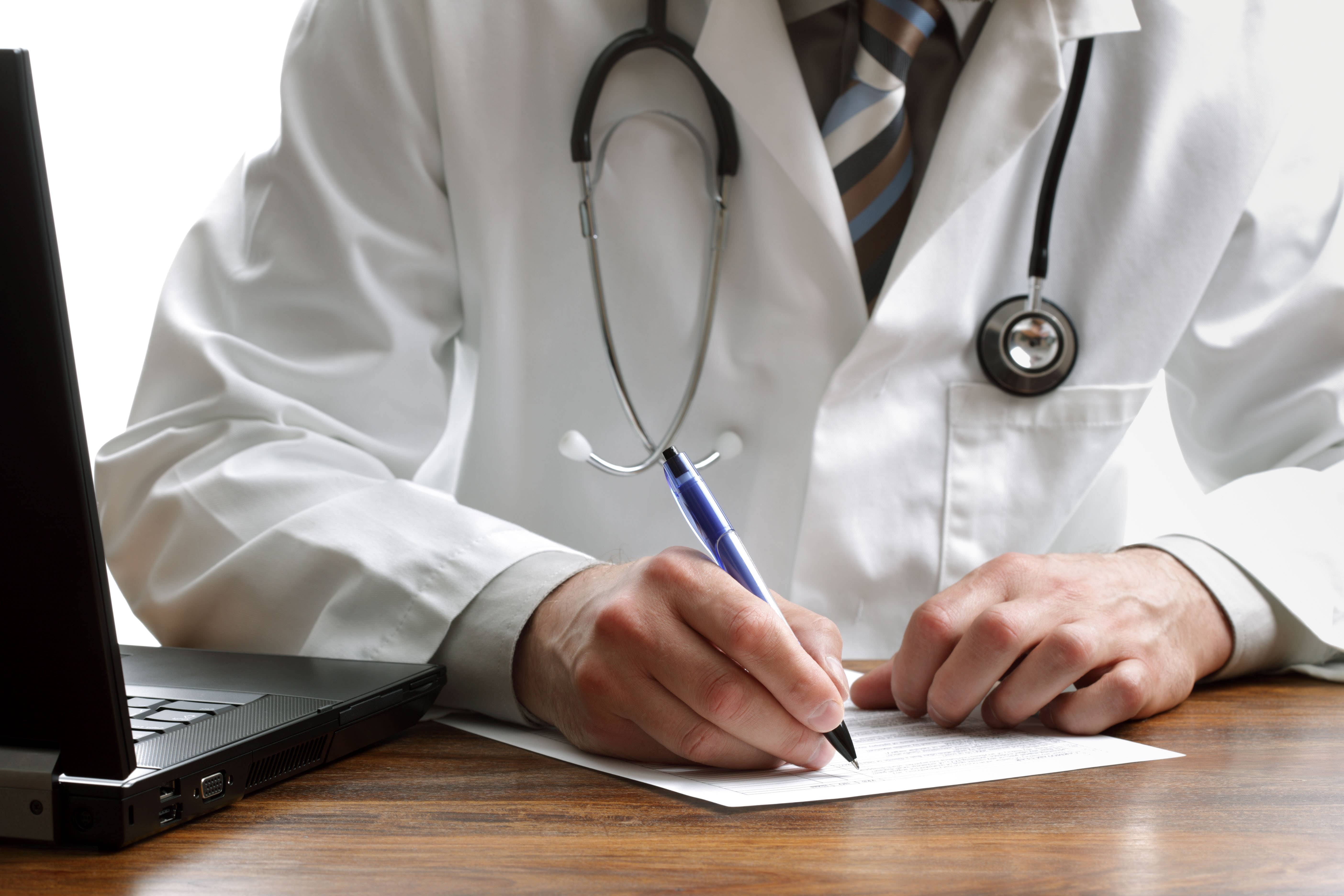 Doctor writing examination notes (Alamy/PA)