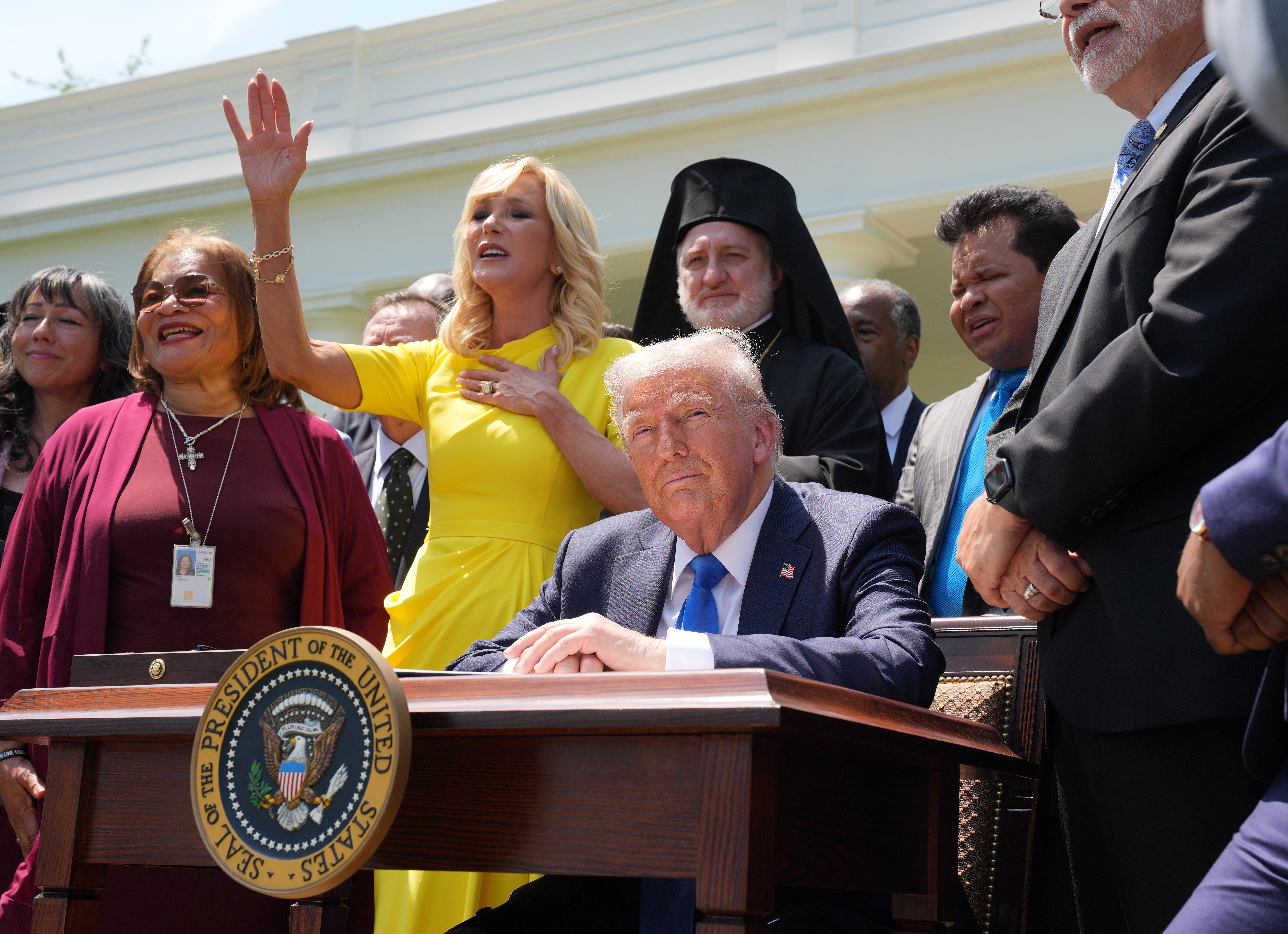 Head of the White House Faith Office, Paula White, sings as she stands next to Trump during a National Day of Prayer event in the Rose Garden with other religious leaders