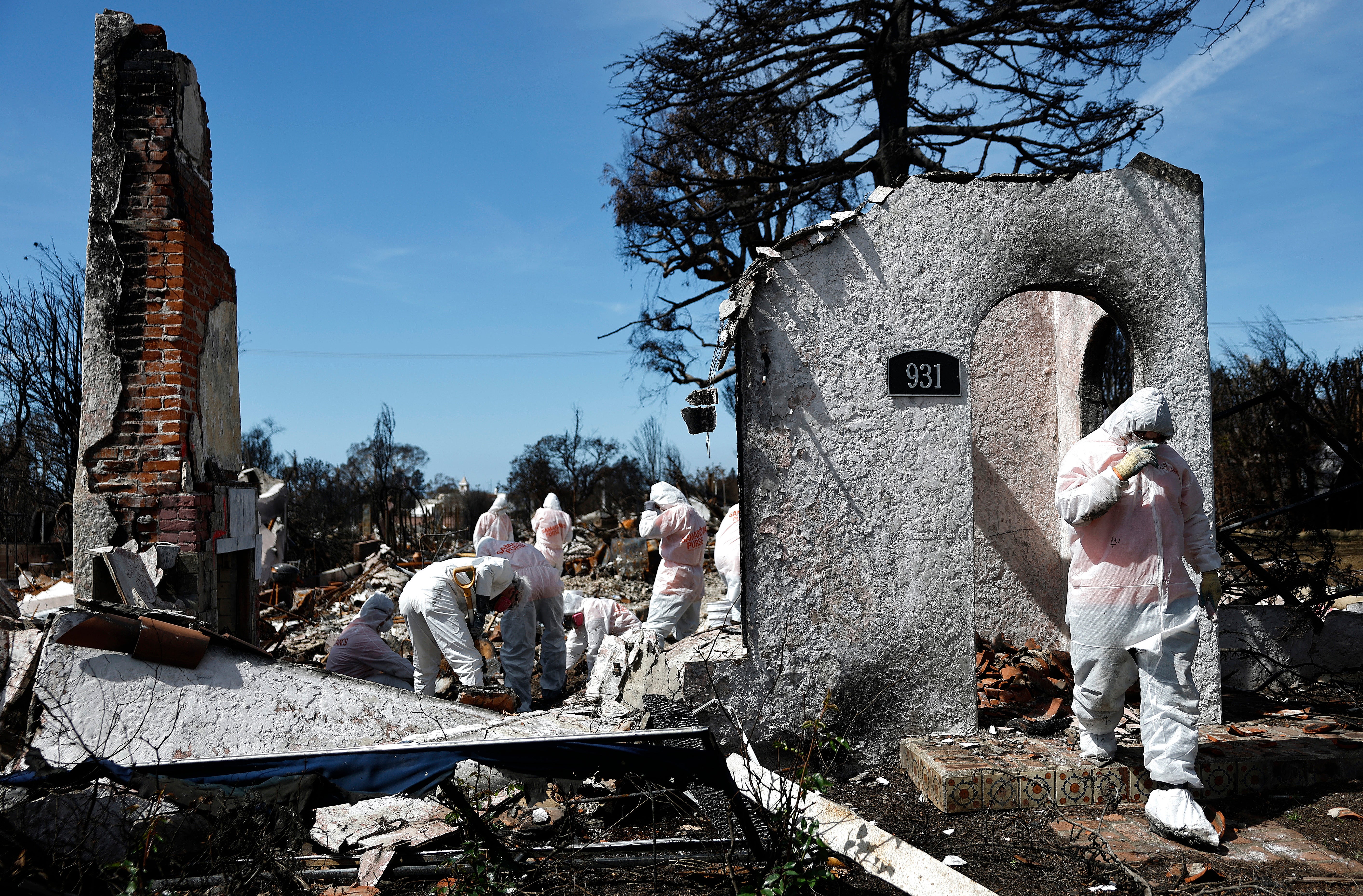 Volunteers help a homeowner search for personal items after his home was destroyed in the catastrophic blazes