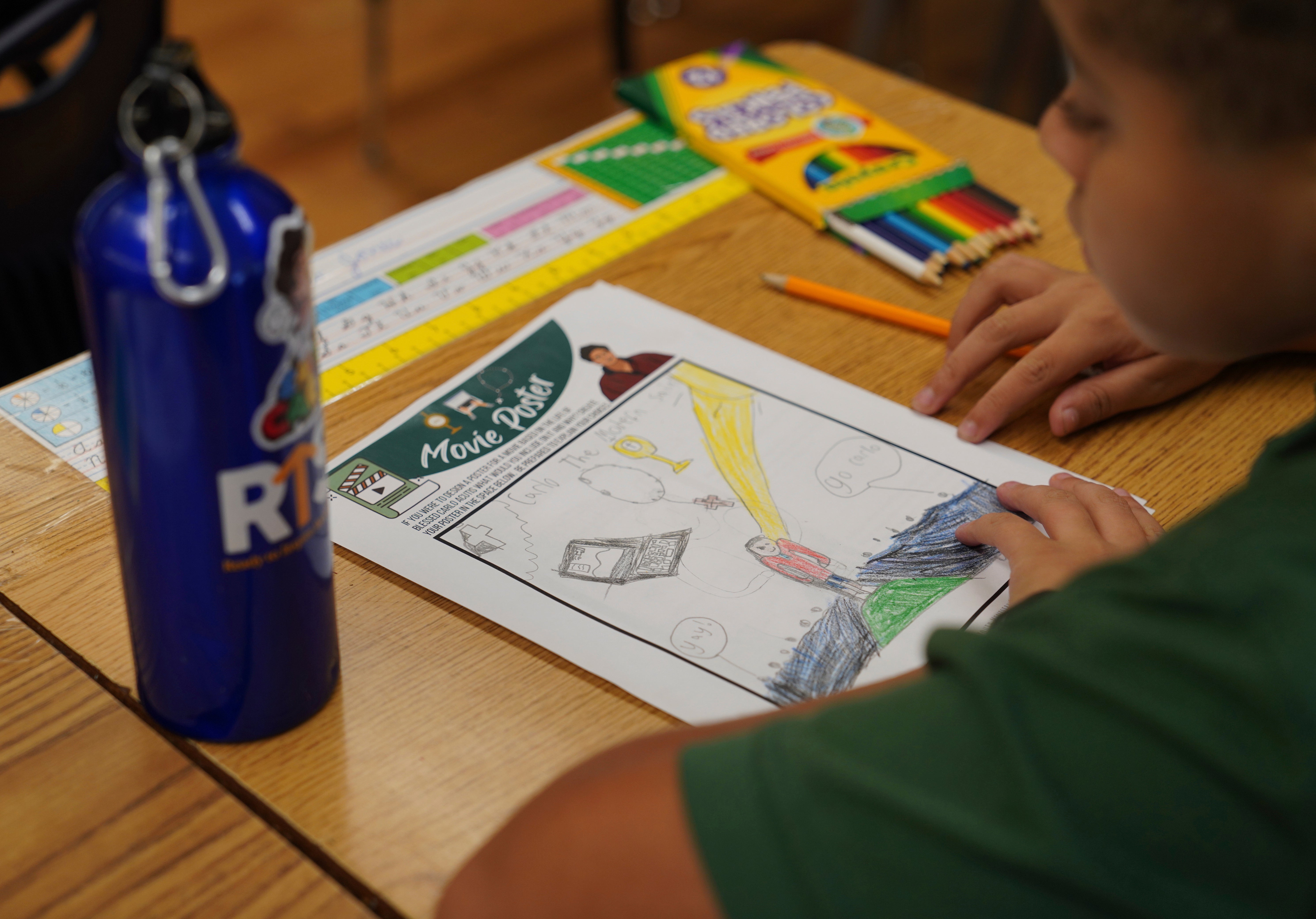 Mateo Jones, a fifth-grade student at St. John Berchmans' school, draws a picture of Blessed Carlo Acutis during a class activity