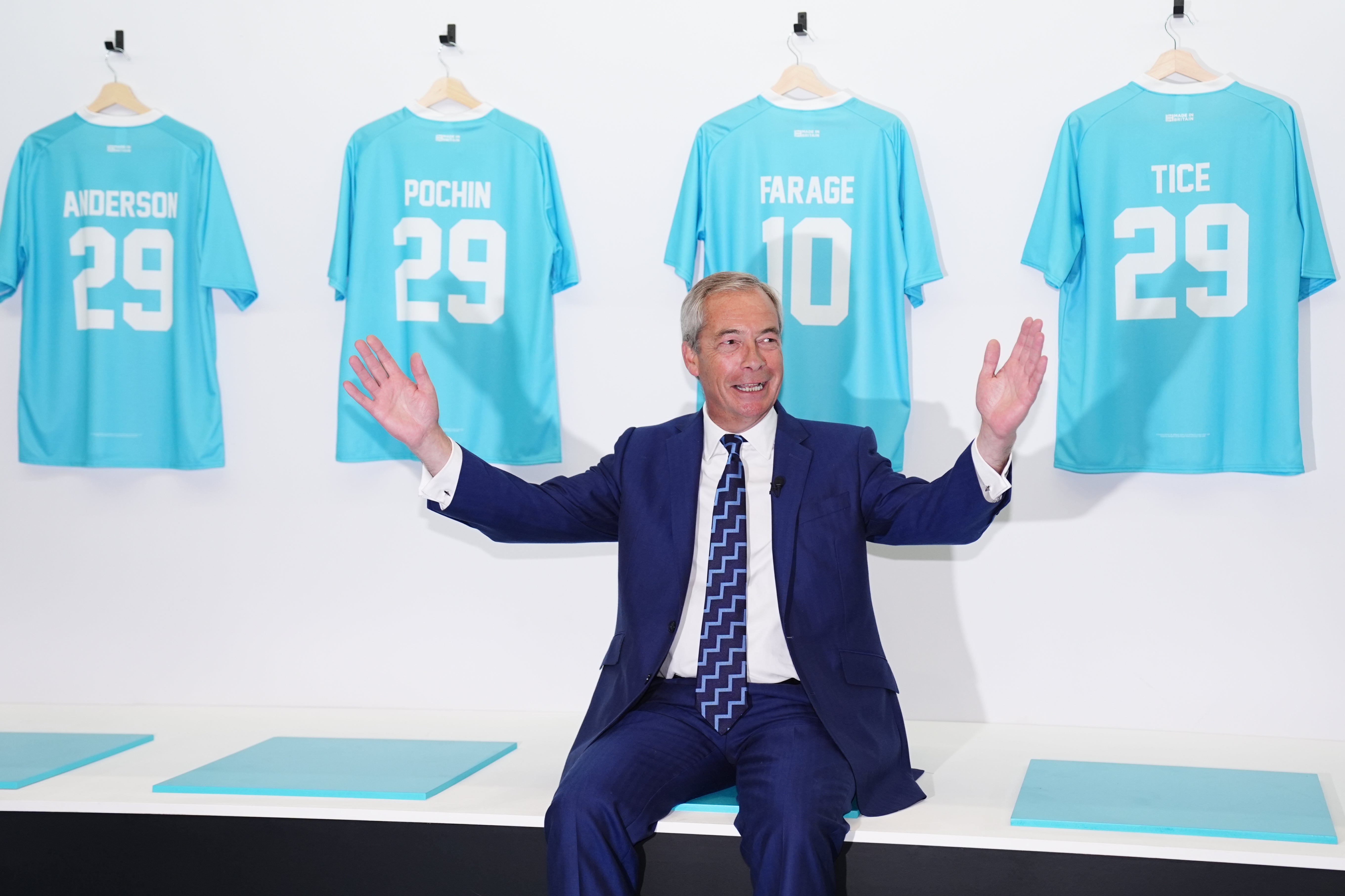 Nigel Farage poses with his party’s football shirts
