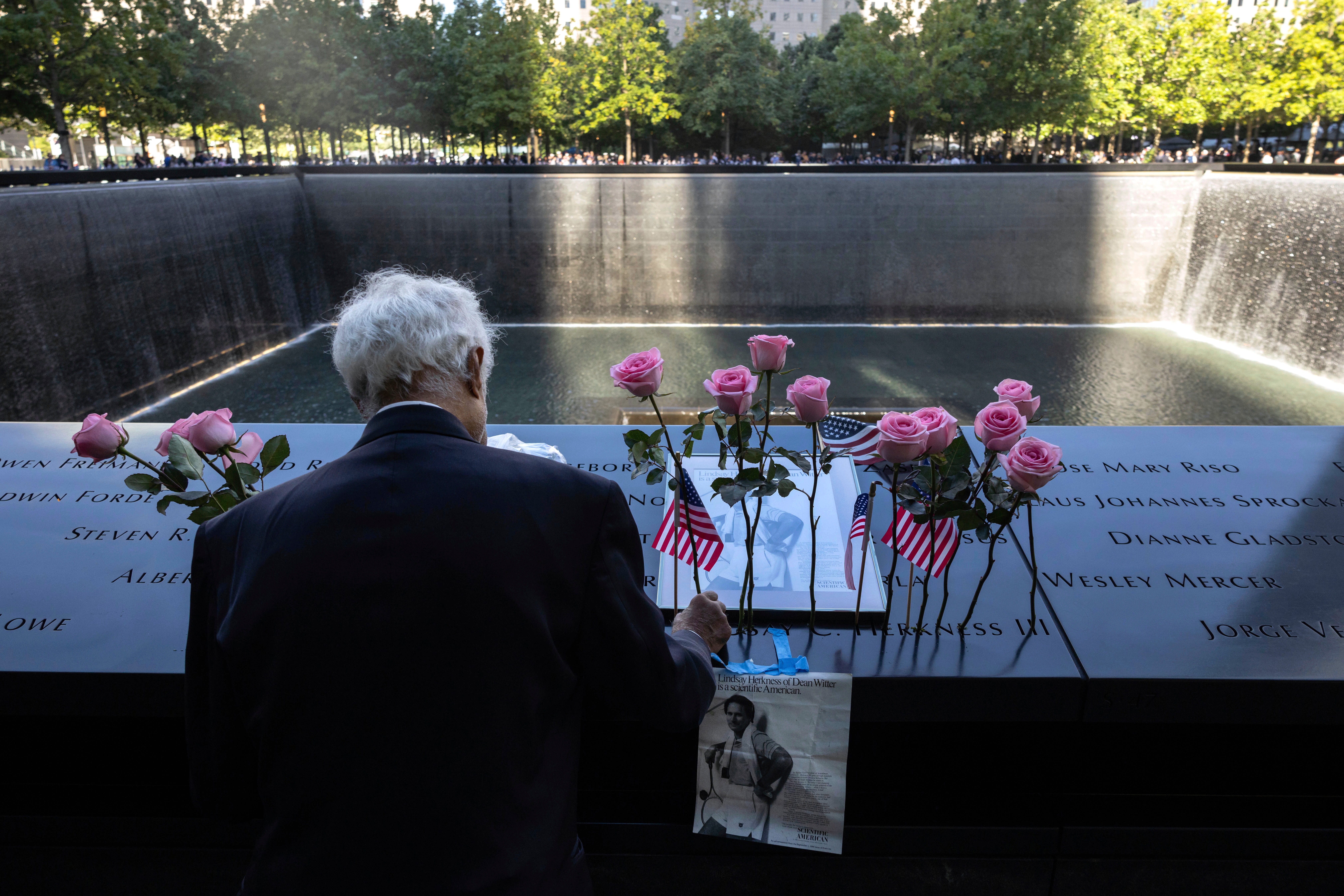 Hagi Abucar places flowers for his former coworker Lindsey Herkness on the south reflecting pool during the 9/11 Memorial ceremony